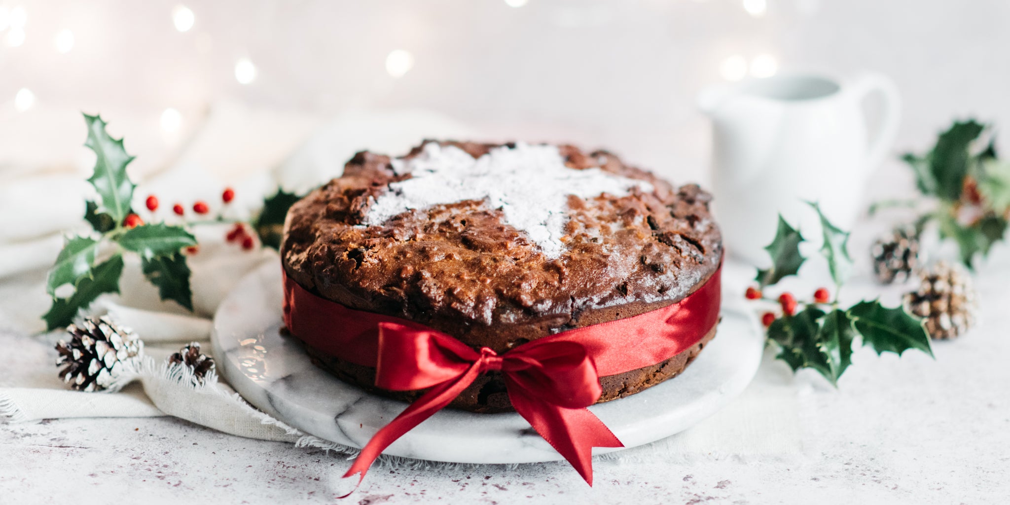 Christmas cake dusted with icing sugar and wrapped with red ribbon