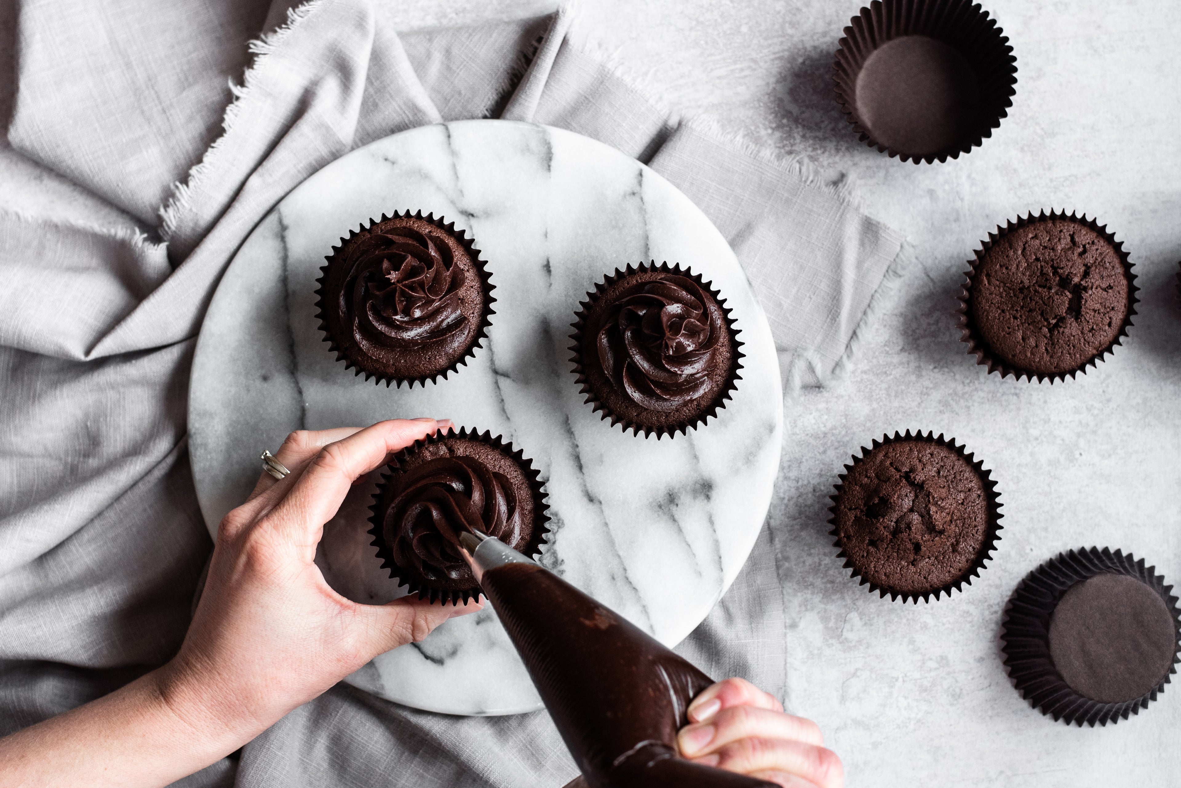 Chocolate cupcakes being frosted with chocolate buttercream