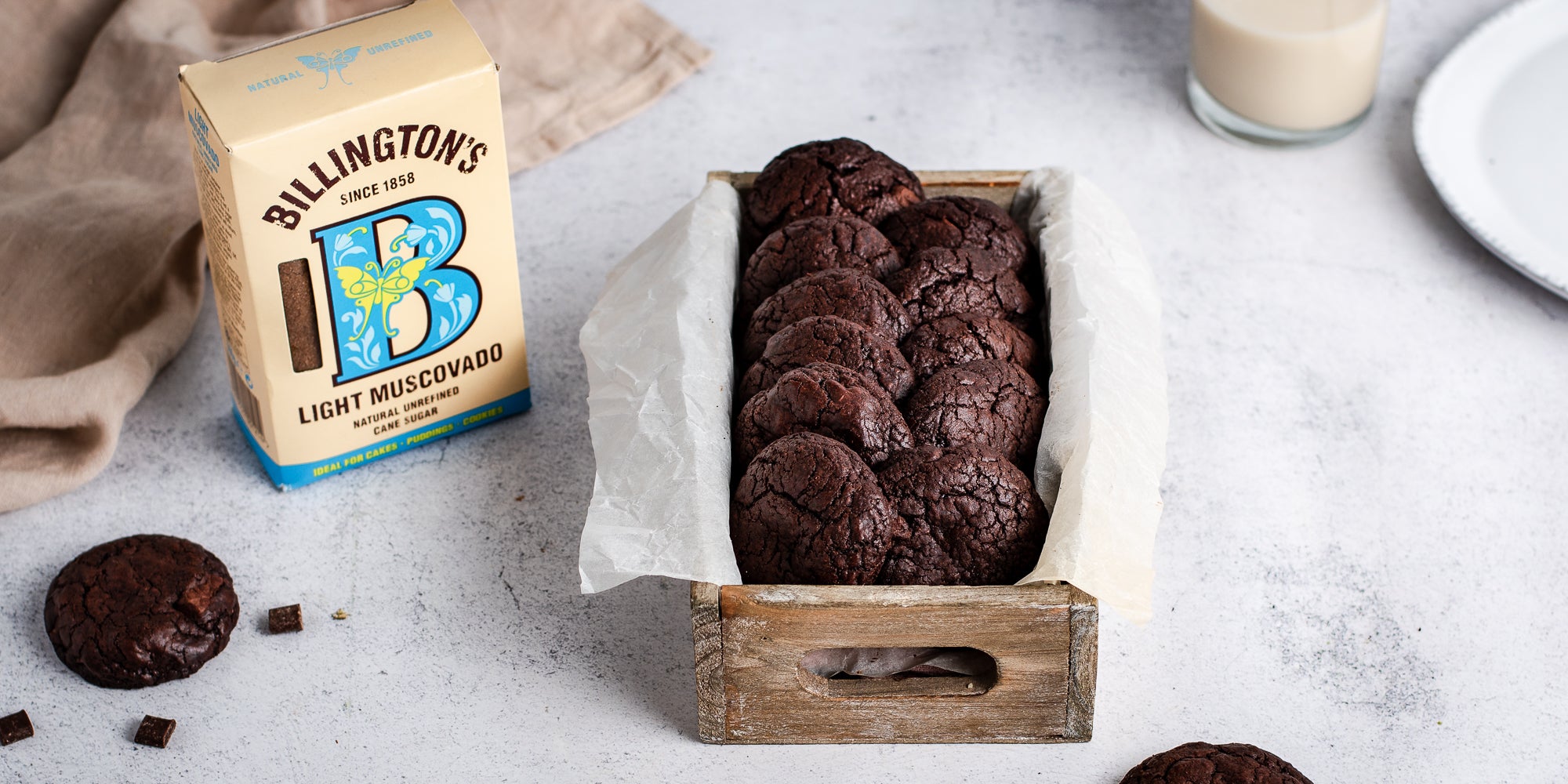 Chocolate Brownie Cookies in parchment paper in a wooden box next to a box of Billington's Light Muscovado Sugar