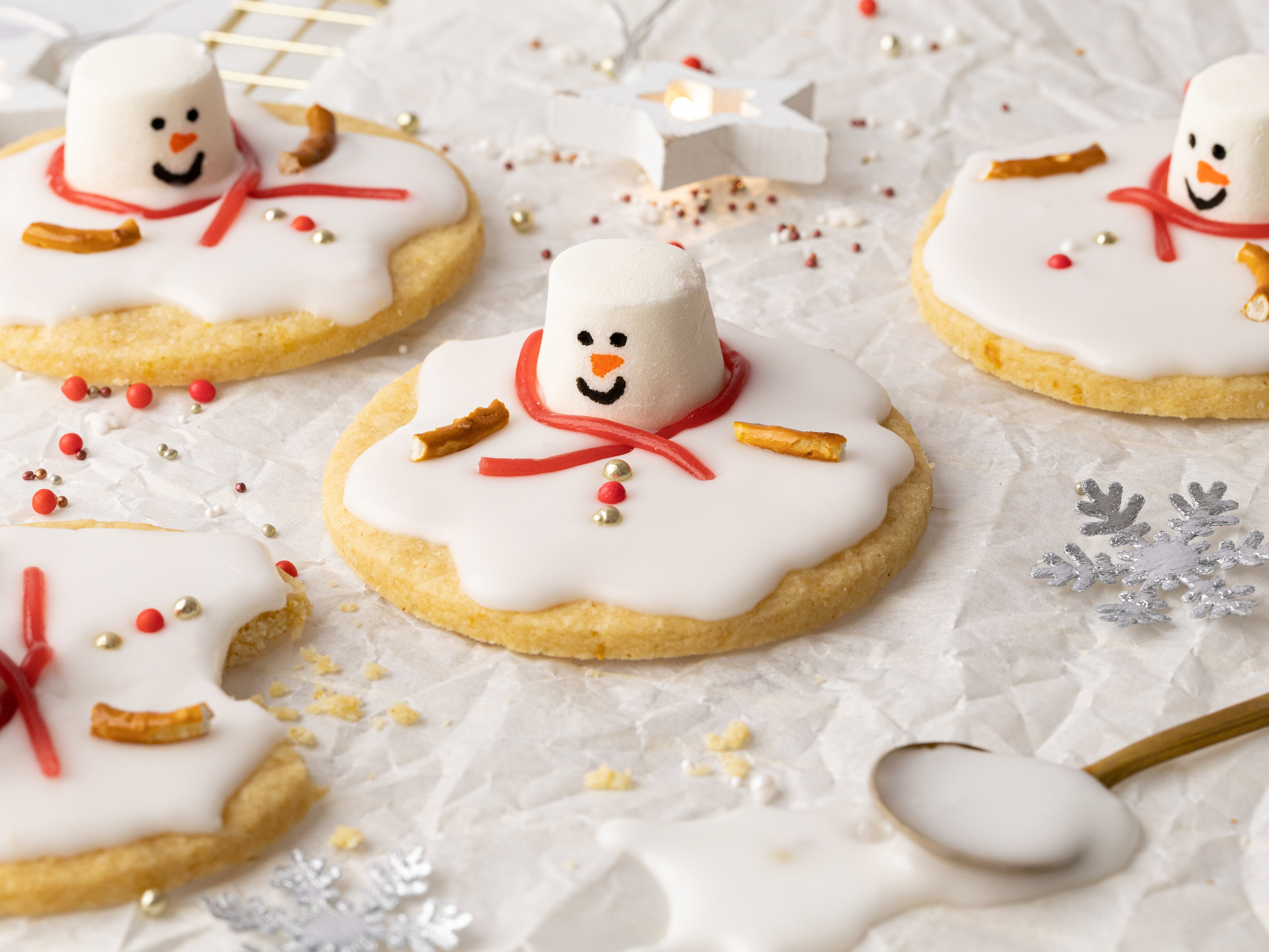 Biscuits topped with marshmallow and icing decorated like a snowman