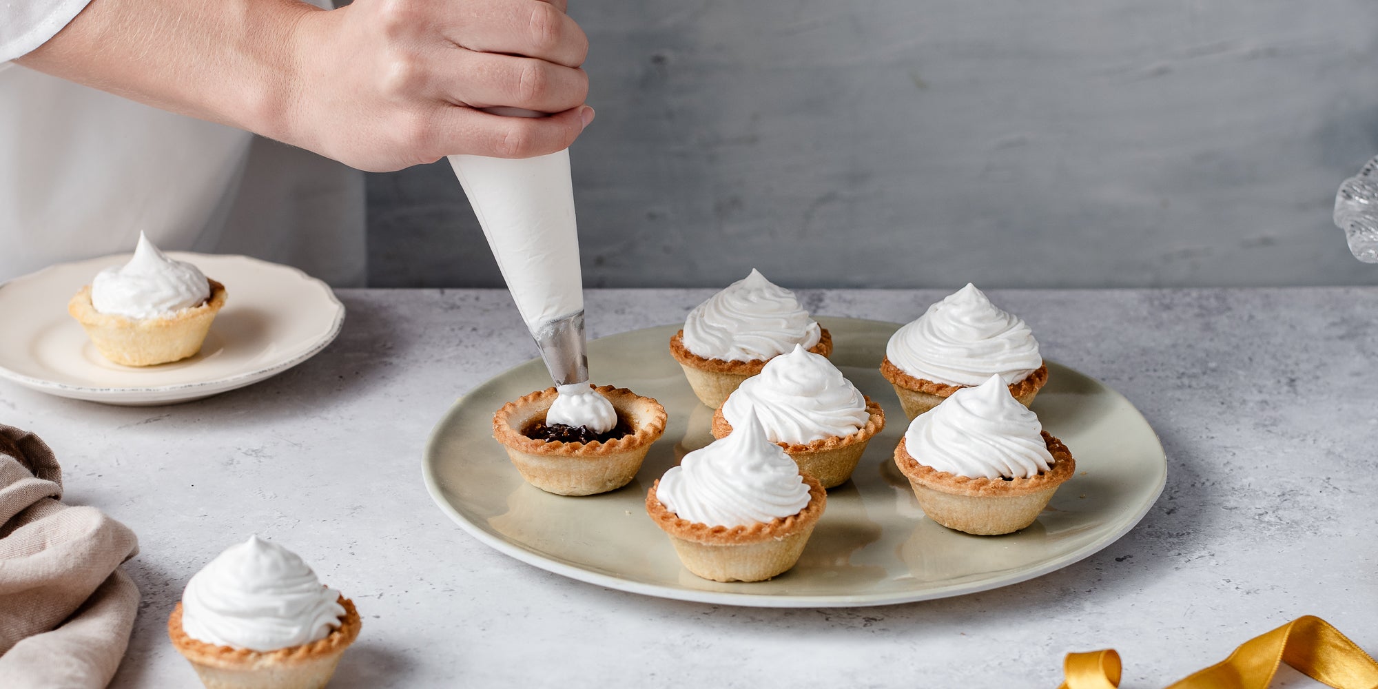 Meringue Topped Mince Pies being hand piped with meringue on a serving plate