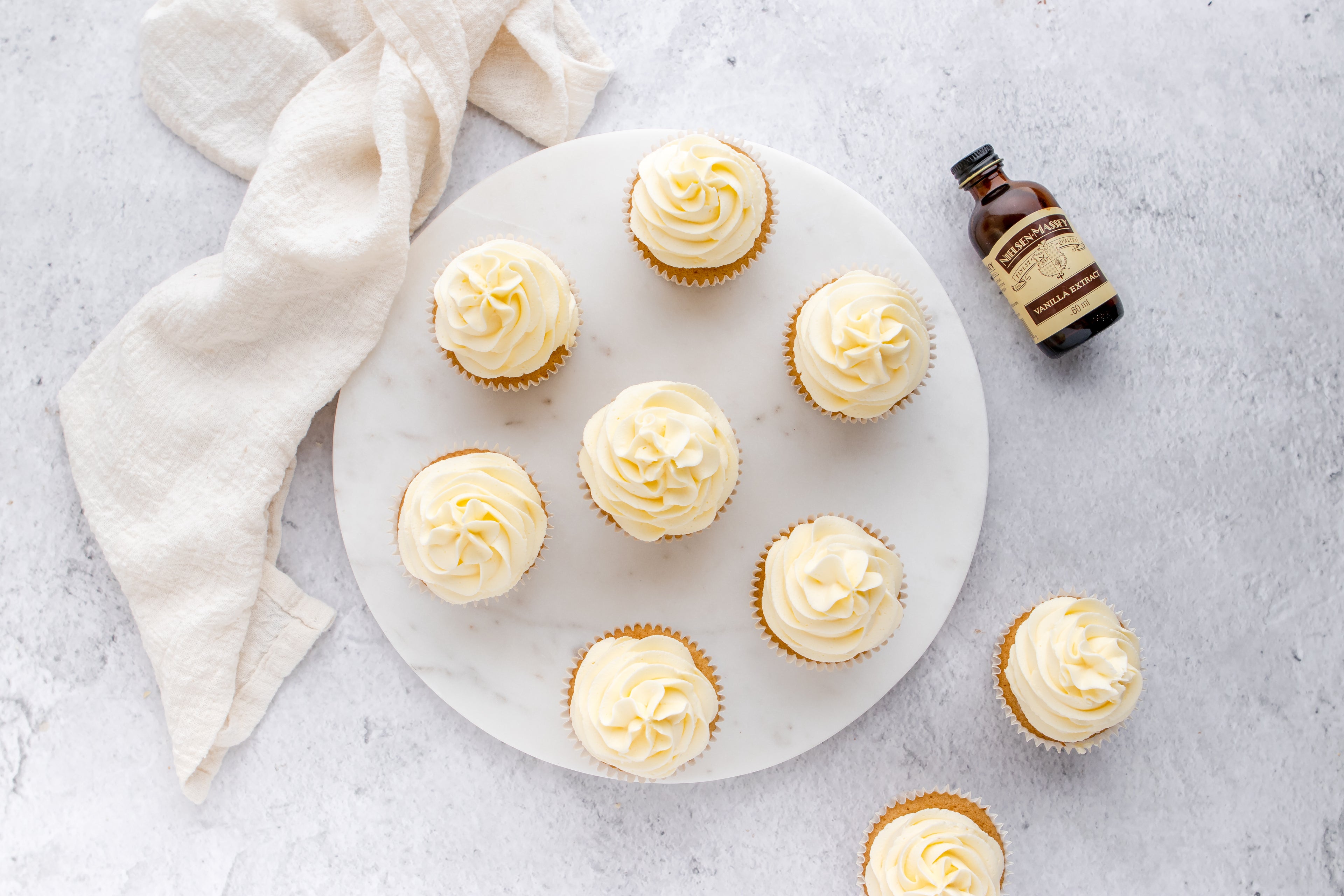Gluten Free Cupcakes from above view with a bottle of Neilsen-Massey vanilla extract lay next to the serving board