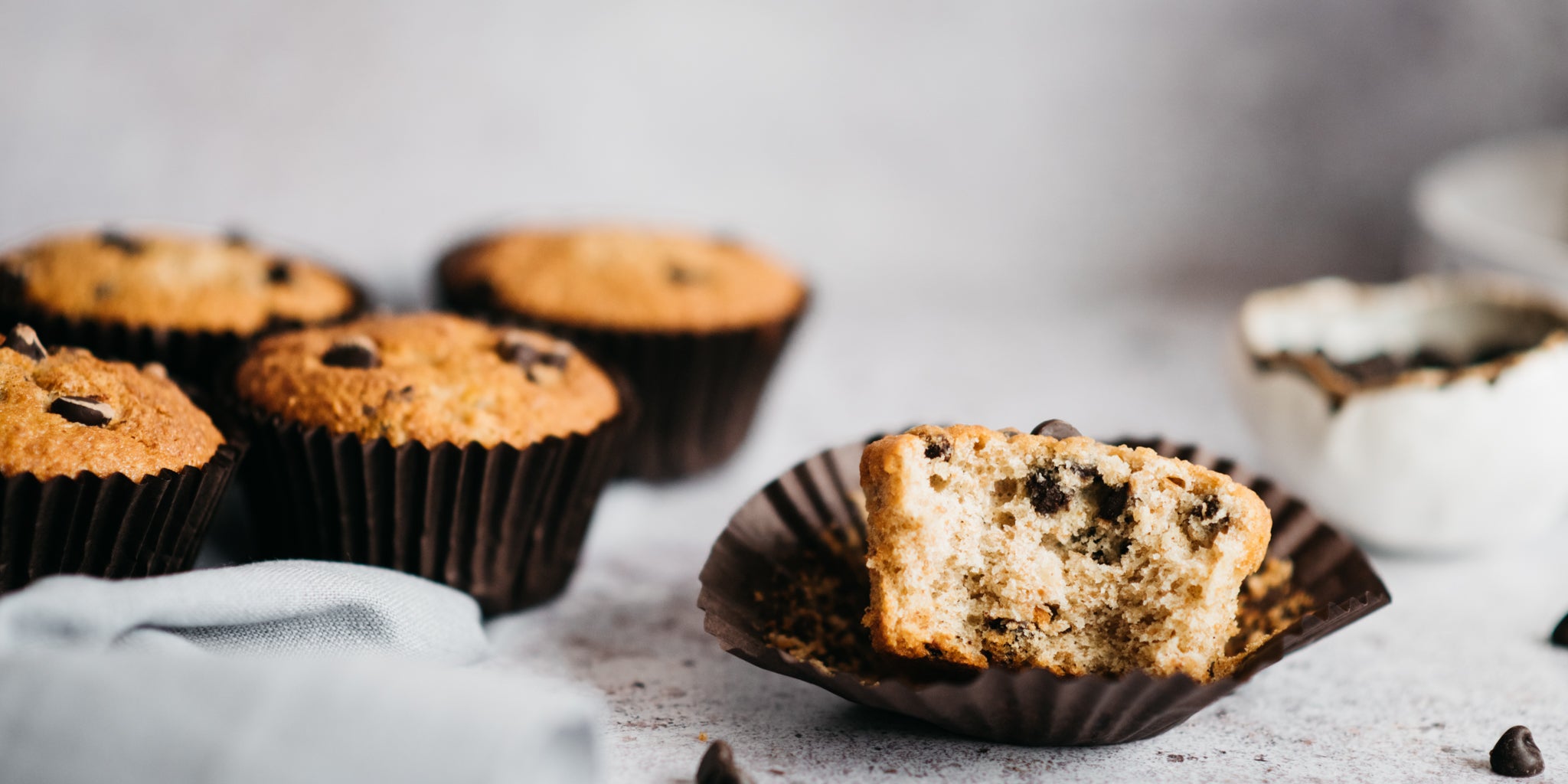 Close up of Wholemeal Banana & Chocolate Chip Muffins with a bite taken out of it showing the rich chocolate chip filling