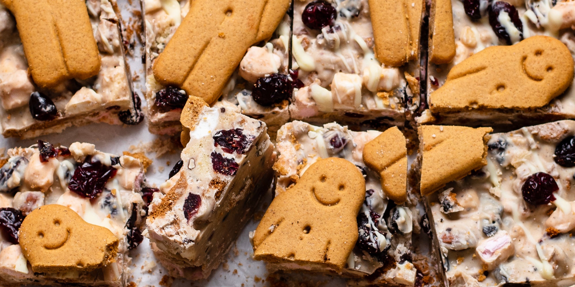 Close up of White Chocolate & Cranberry Rocky Road cut into squares with gingerbread men as a topping