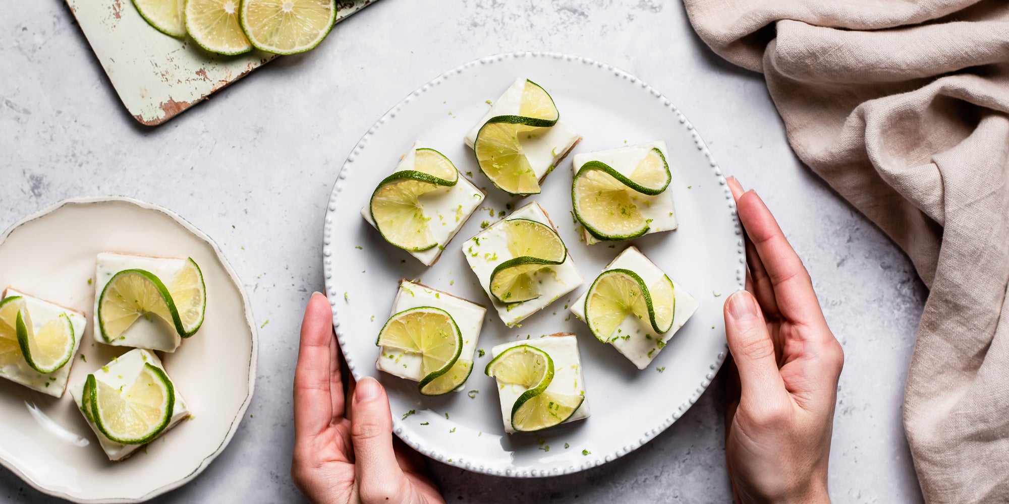 Hands holding a plate with slices of Margarita Bites topped with slices of twisted lime
