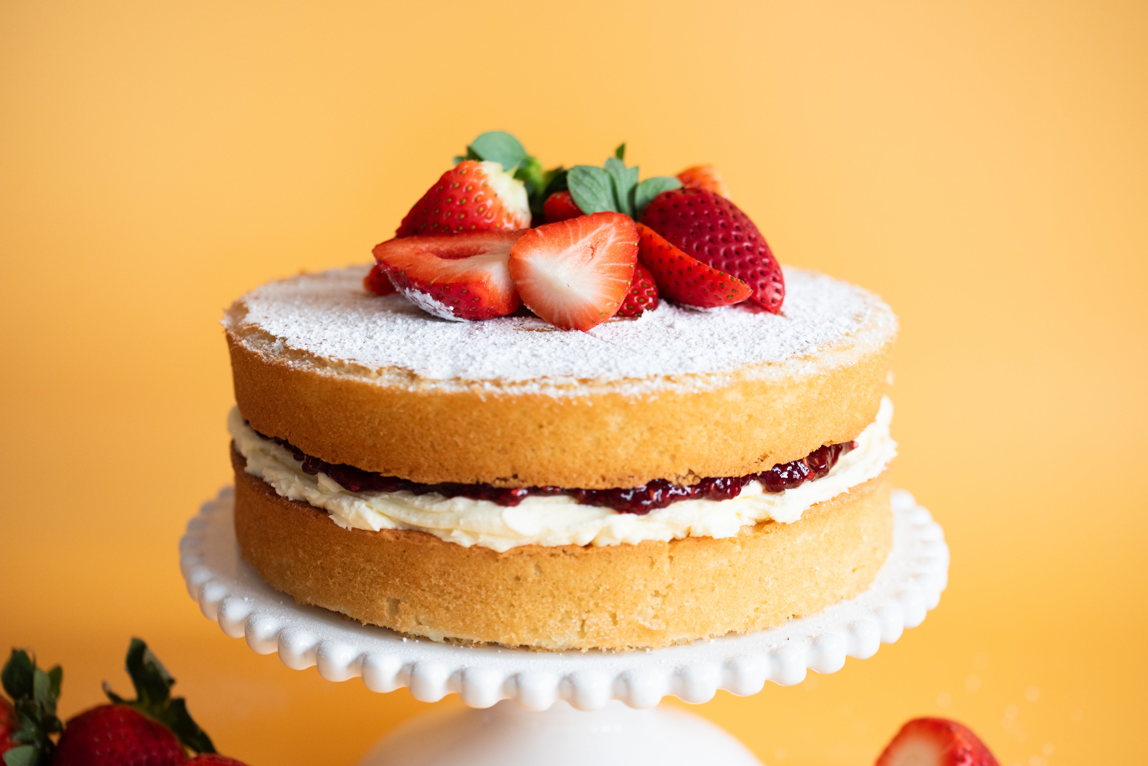Close up of a  Victoria sponge cake on a white cake stand 