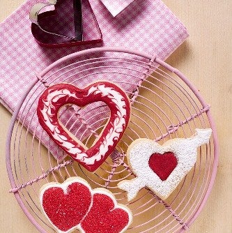 Heart-shaped Valentine's Day cookies decorated with pink icing, cooling on a pink wire rack 