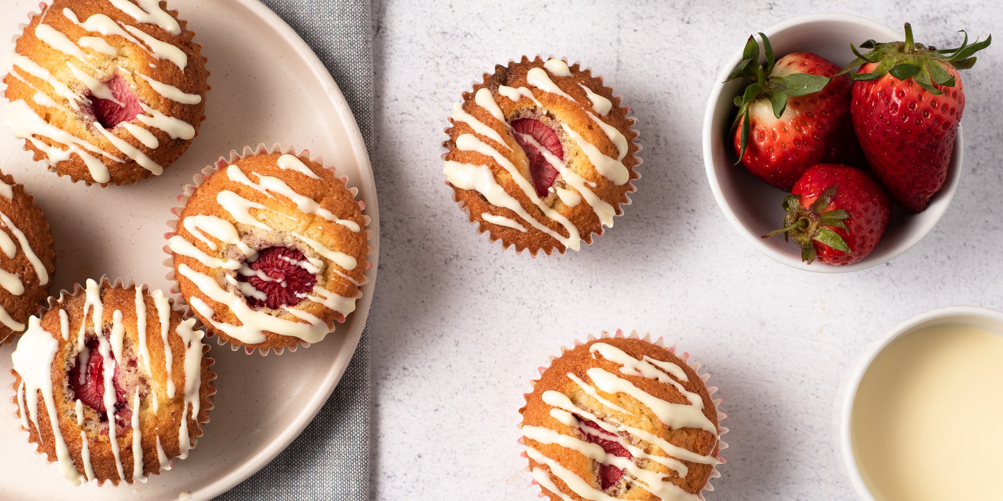 Cupcakes with a strawberry in the centre drizzled with white chocolate