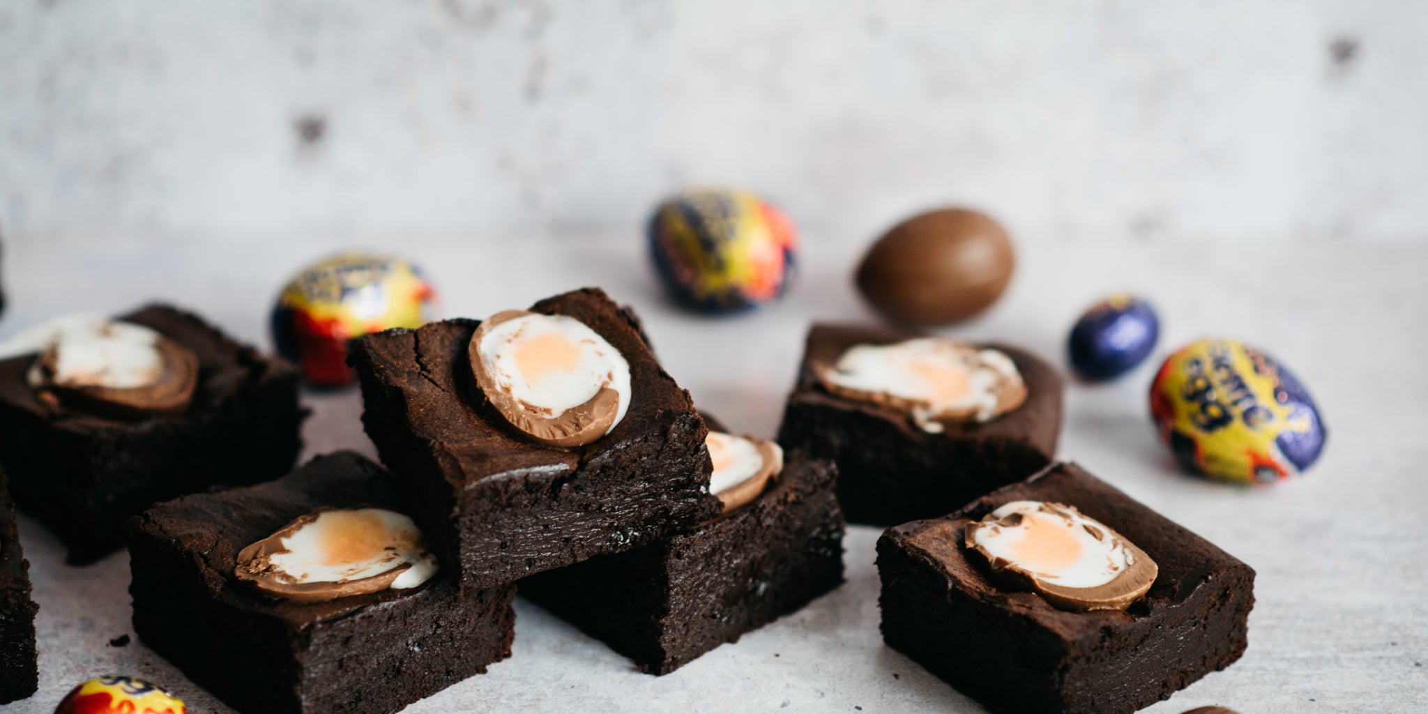 Brownies stacked on top of each other surrounded by creme eggs