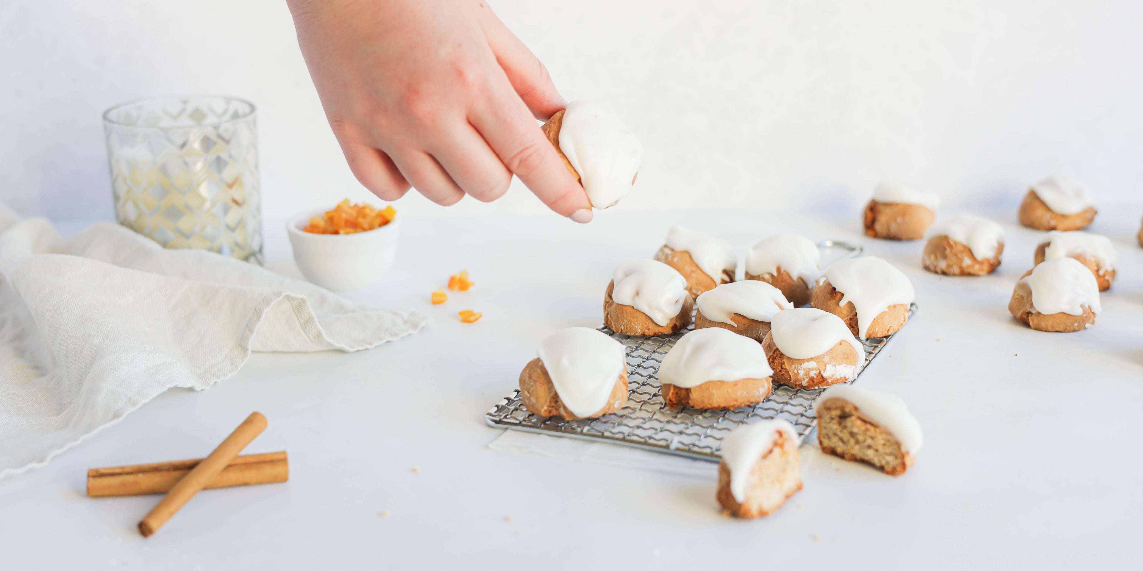 Pfeffernusse on a wire rack, topped with Silver Spoon Icing with a hand reaching for a Pfeffernusse