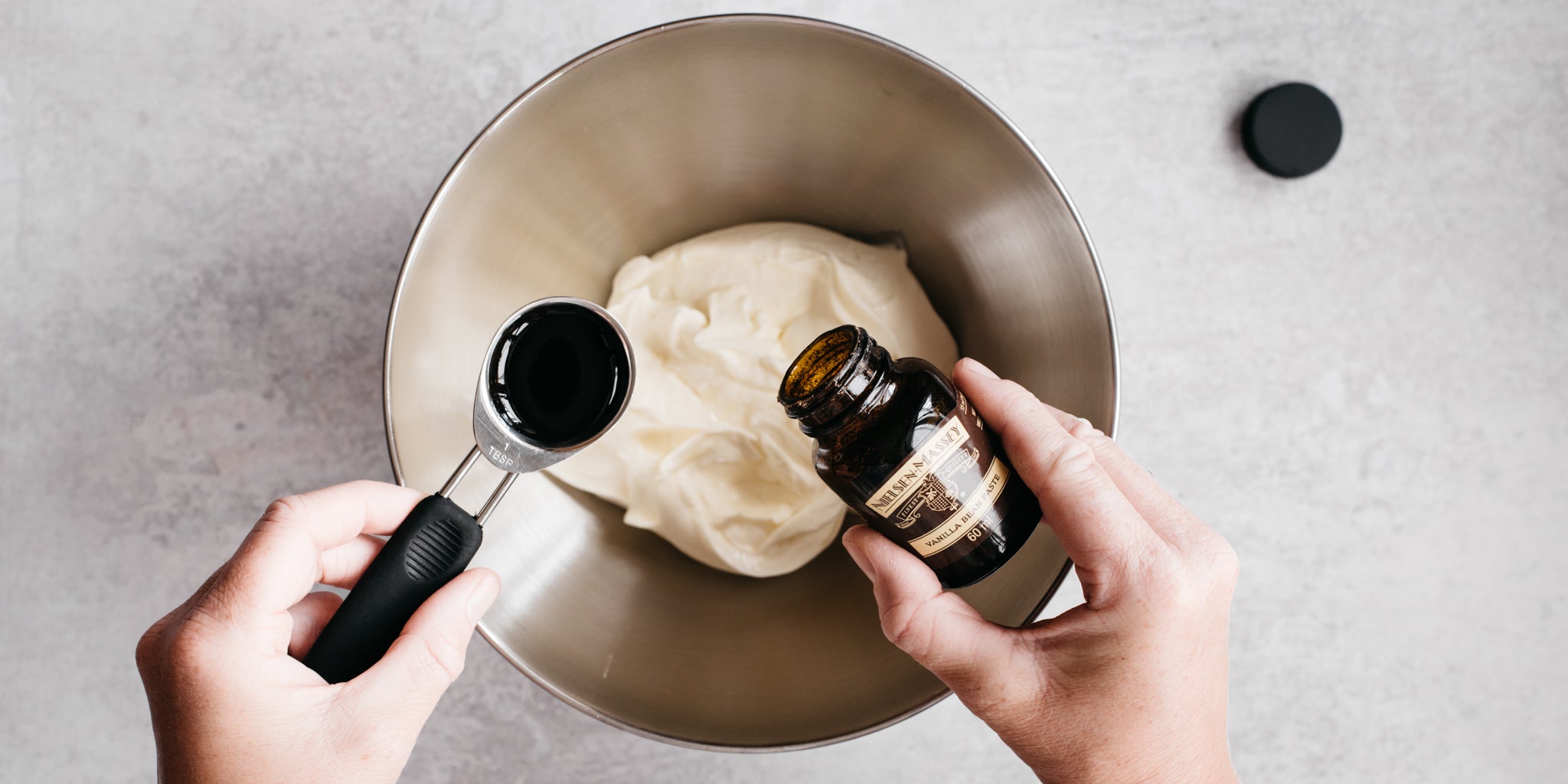 Top down shot of vanilla being poured into cheesecake mixture