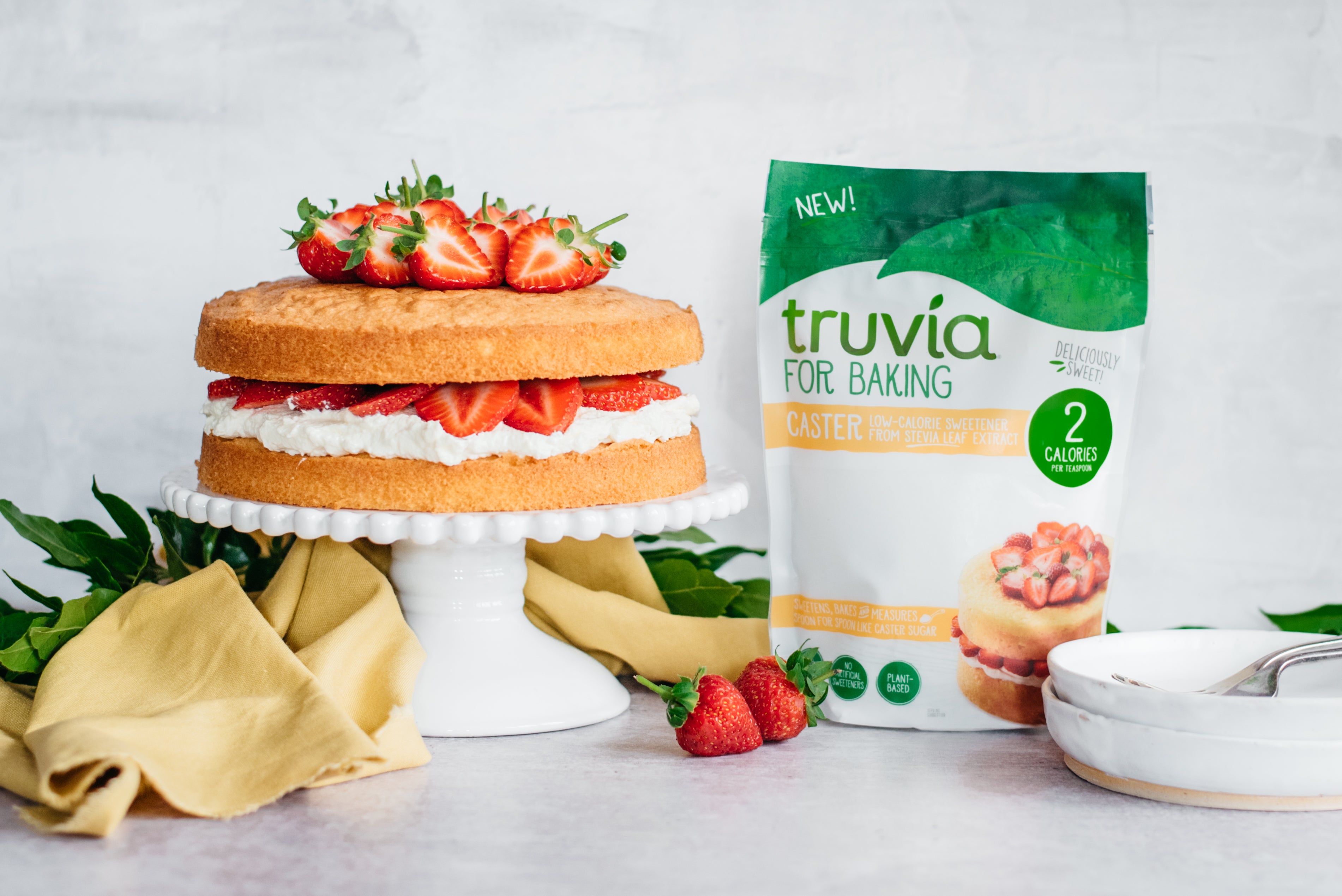 Side on view of a low sugar victoria sponge next to a packet of truvia for baking caster