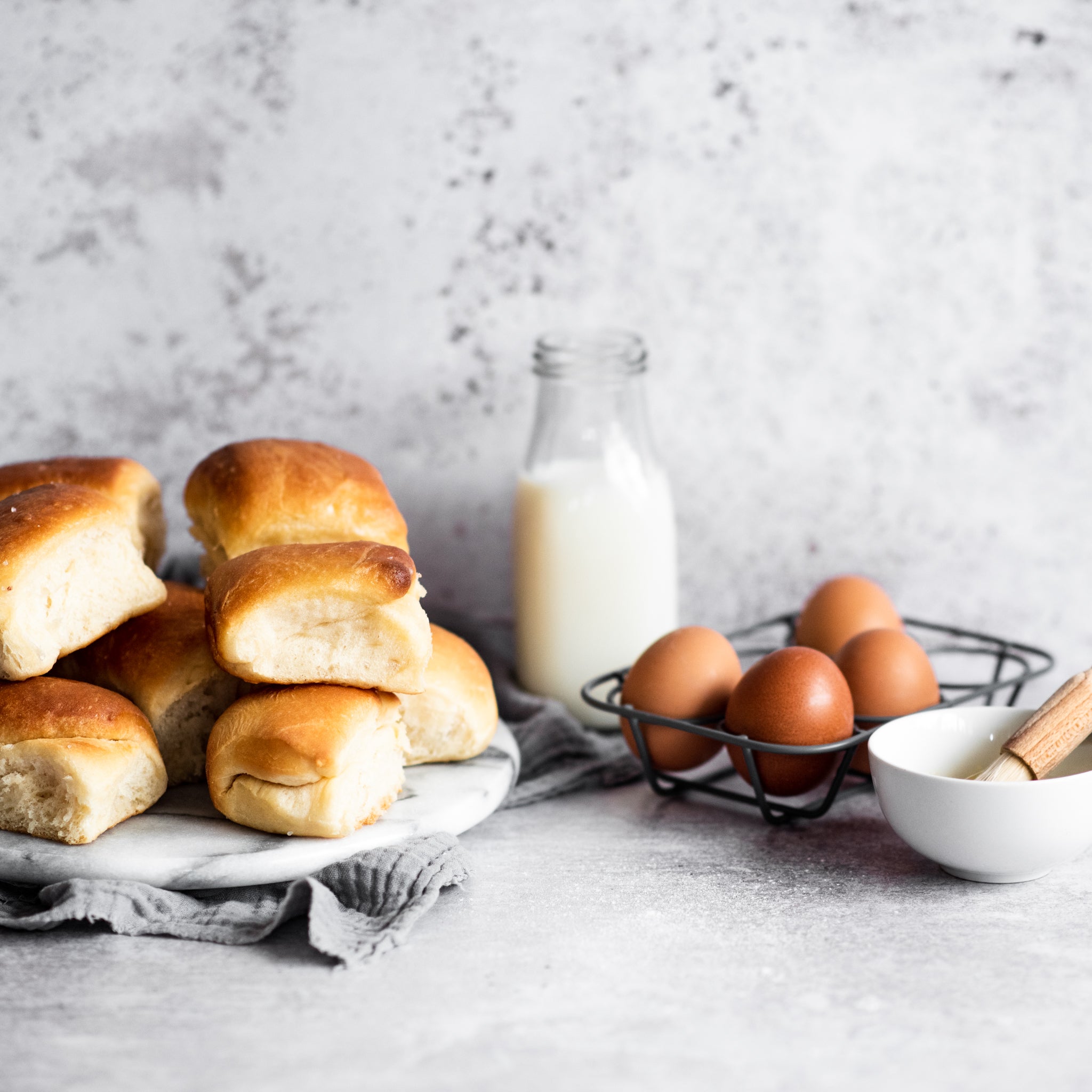  bread rolls on a plate with eggs and milk