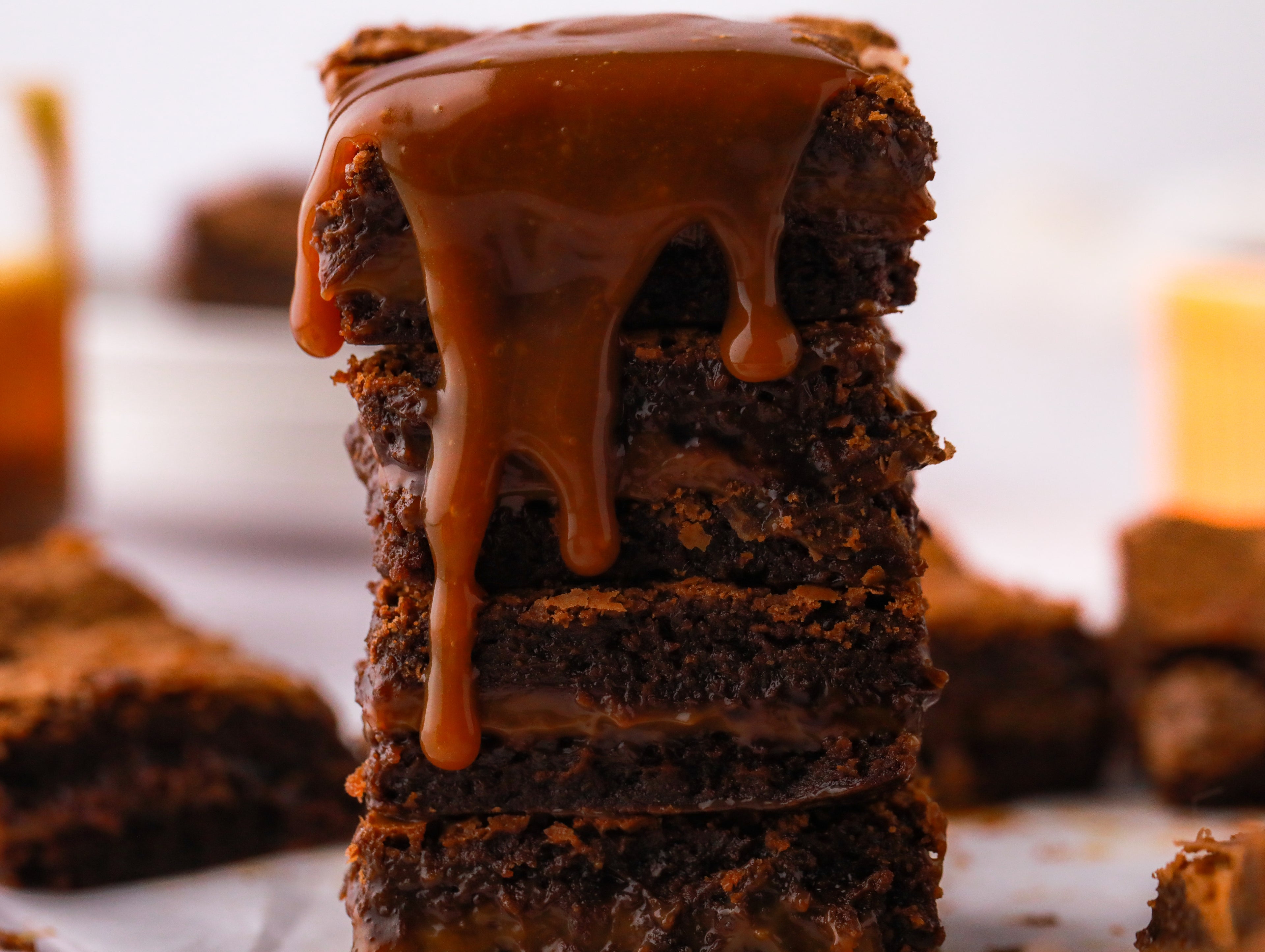 Close up of a stack of brownies with caramel dripping down it