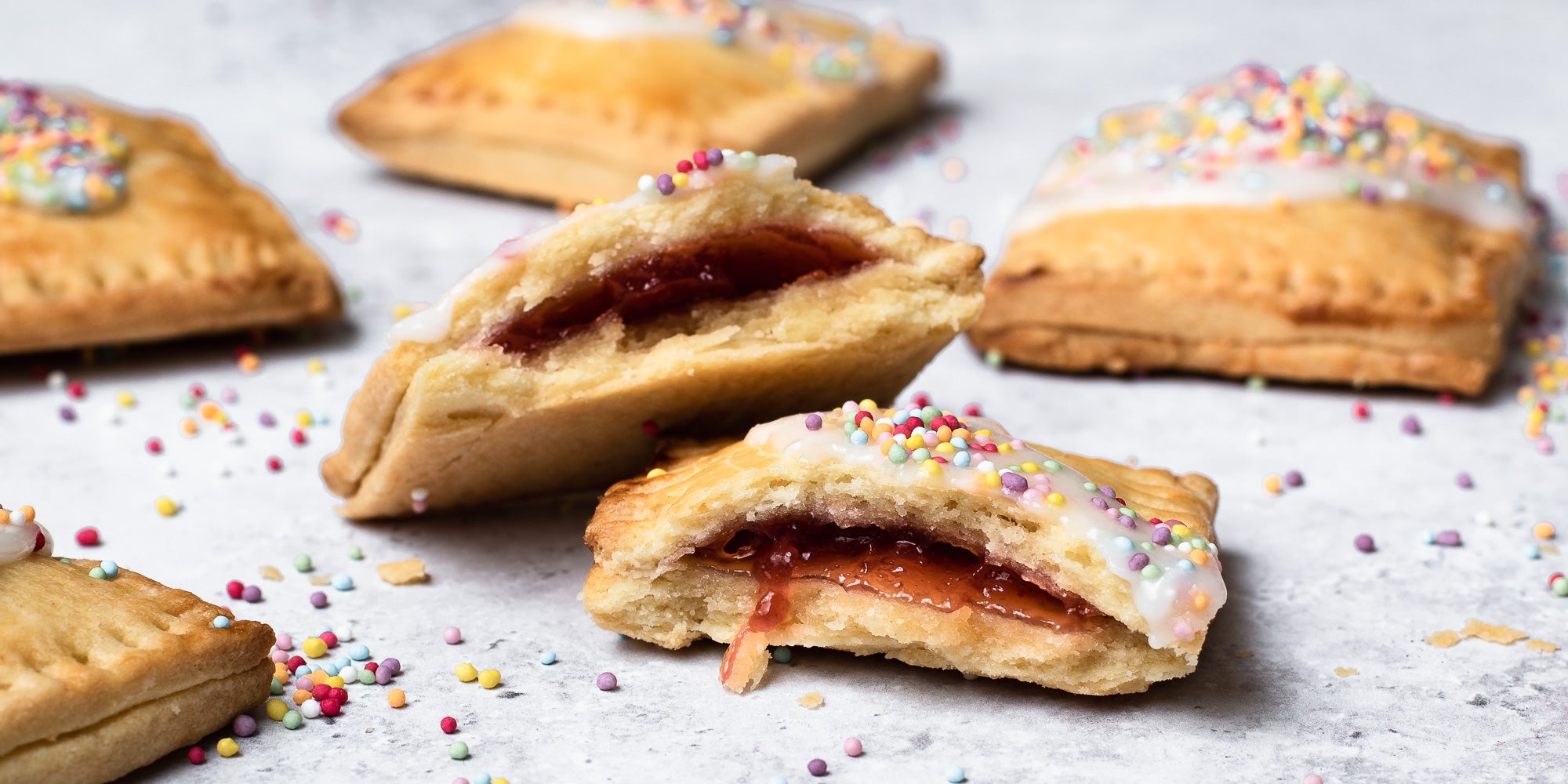 Close up of pop tarts broken in half showing jam in the centre. Other pop tarts in background