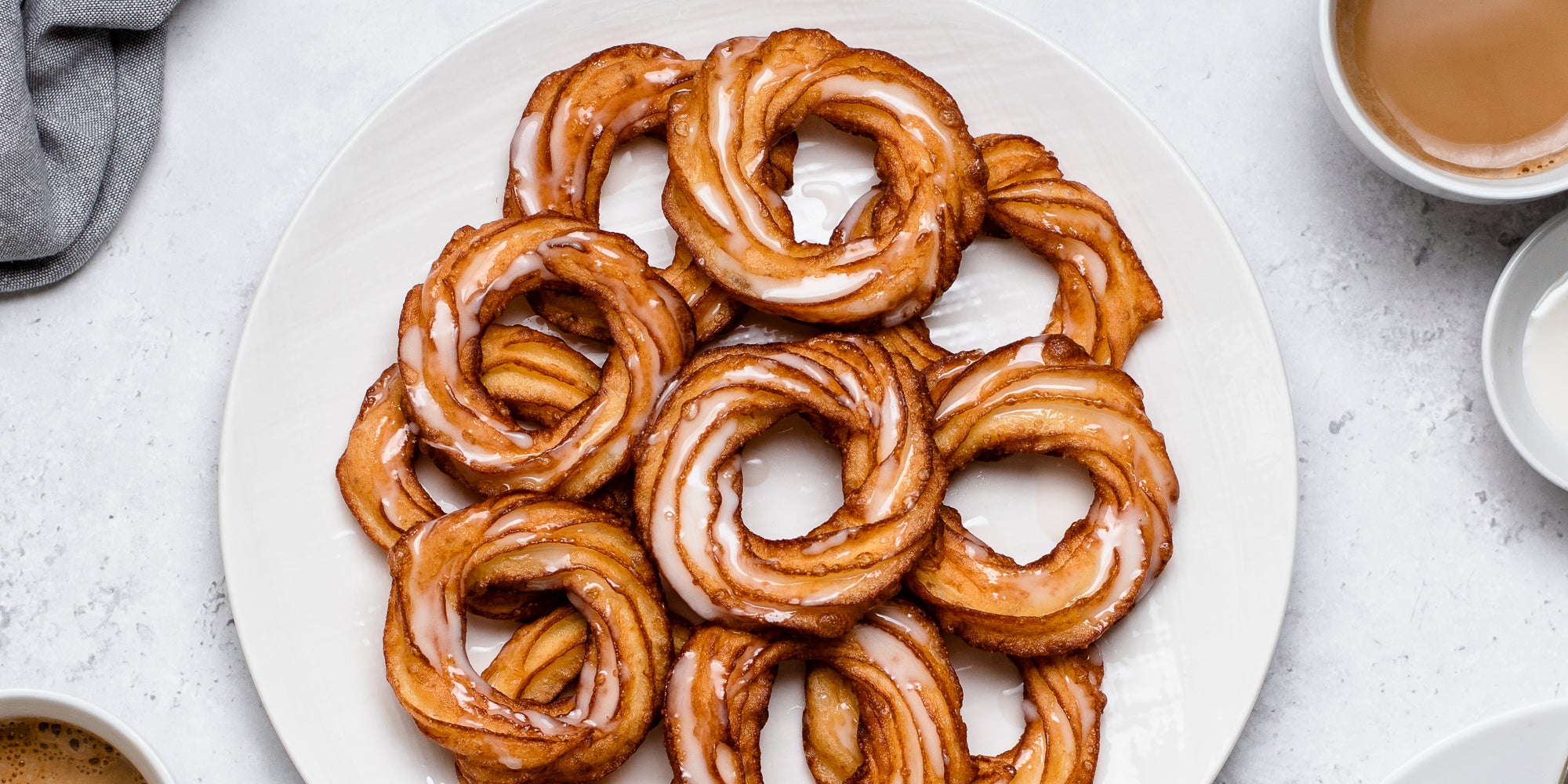 Close up top view of Apple Cider Crullers on a plate, drizzled with icing 