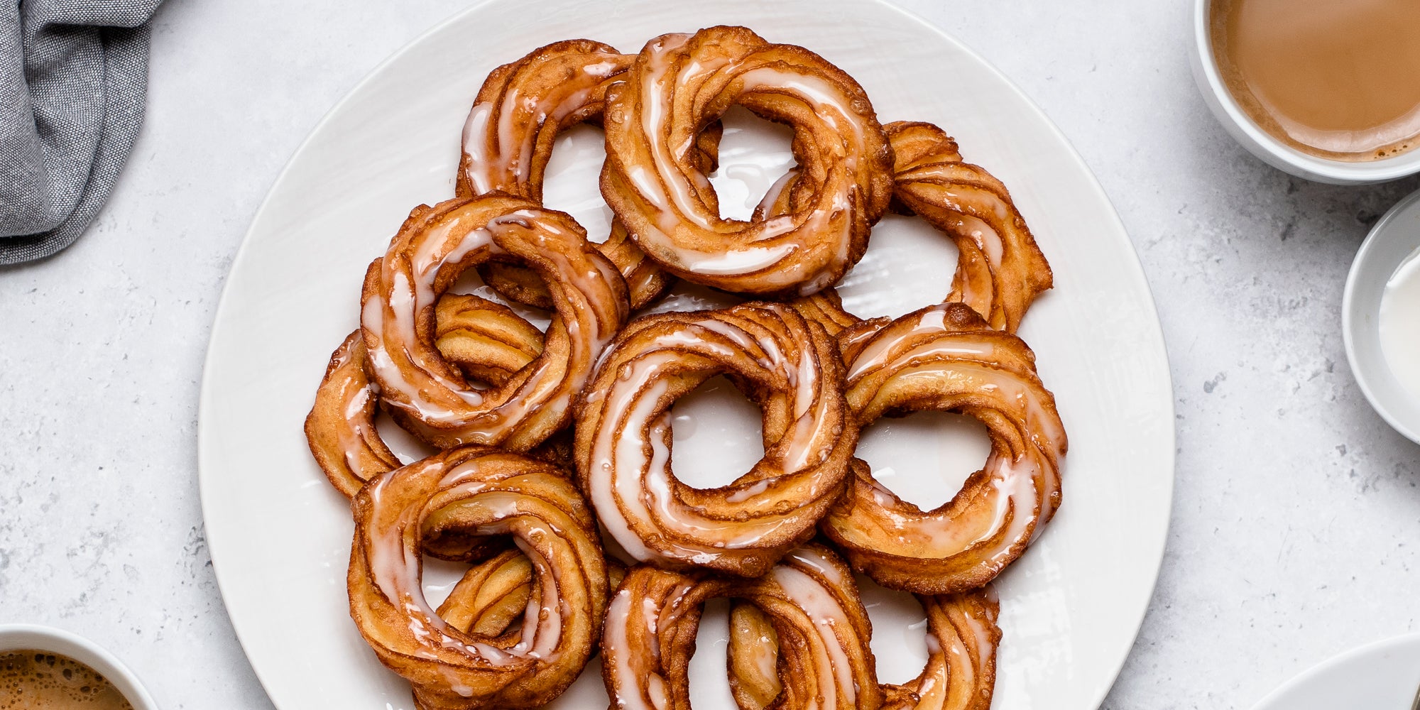 Close up top view of Apple Cider Crullers on a plate, drizzled with icing