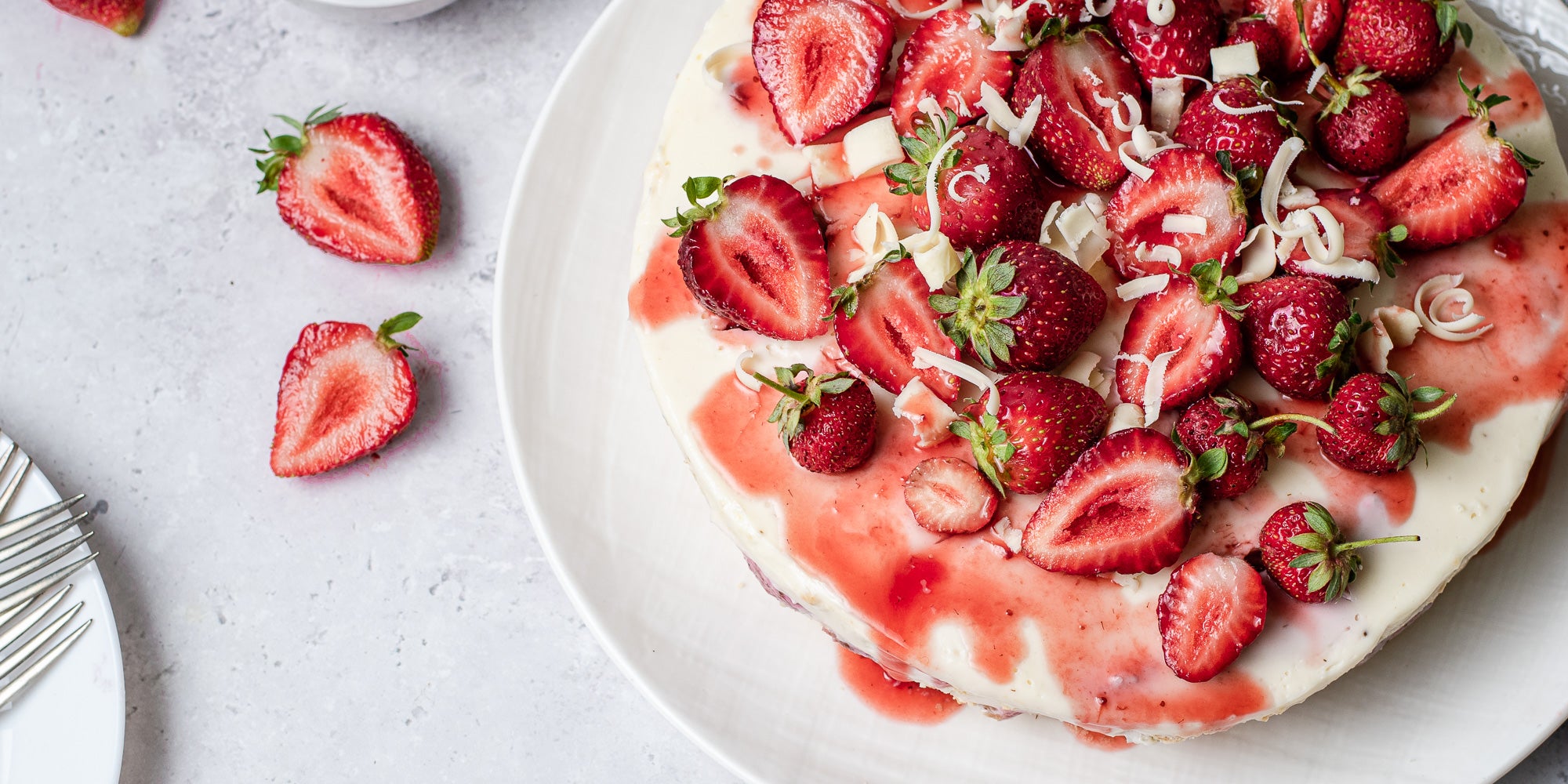 White Chocolate & Strawberry Cheesecake topped with strawberries and white chocolate shavings