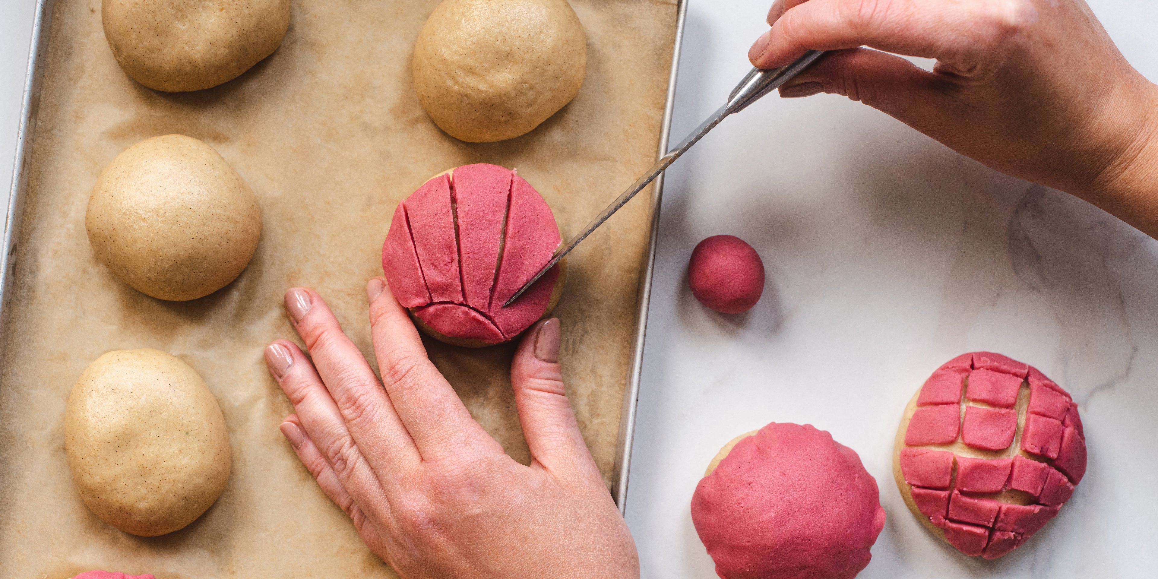 Hands holding a knife, hand decorating the pink layer onto of the Conchas balls