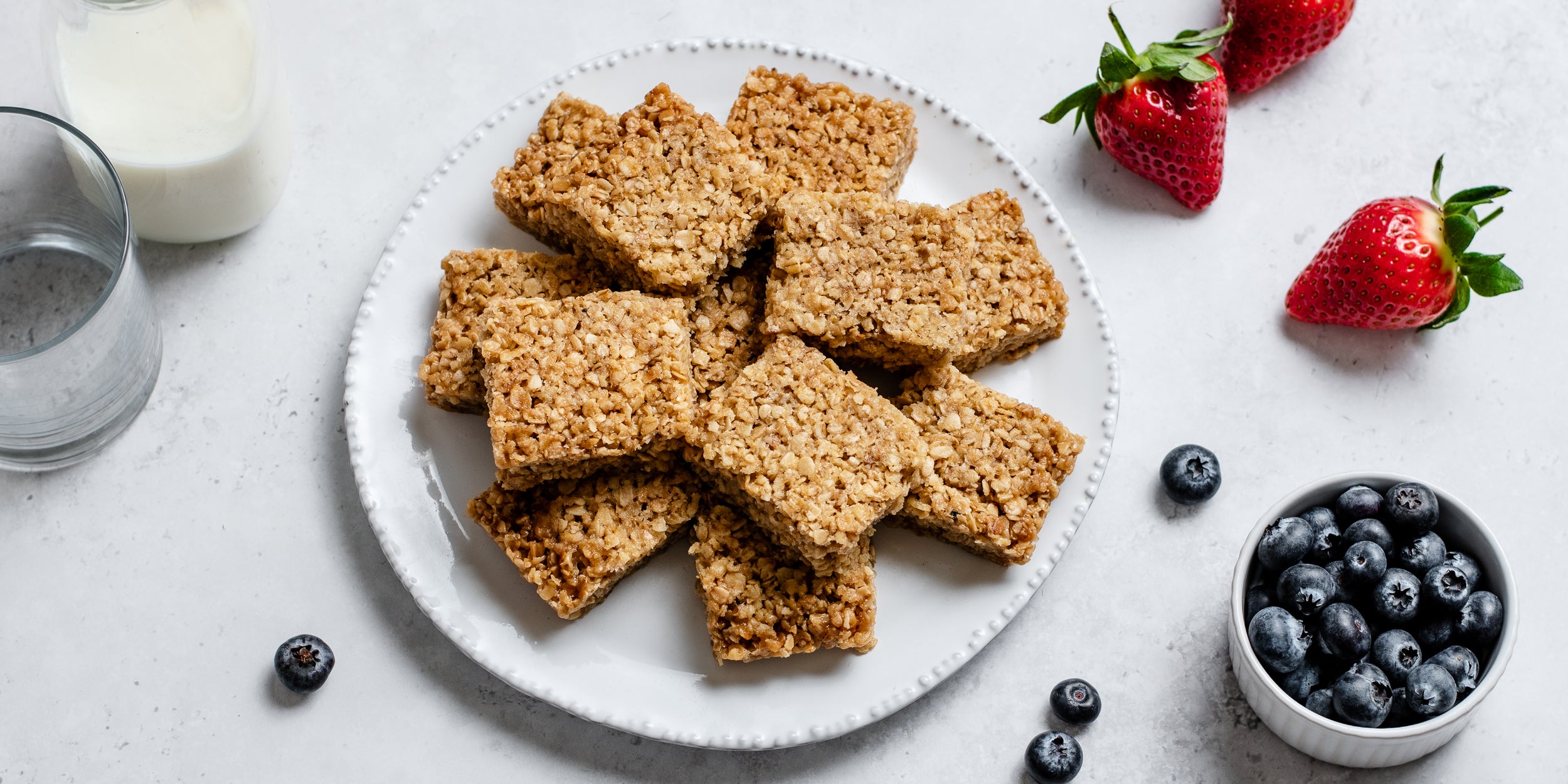 Top view of a batch of Easy Flapjacks served on a plate, next to fresh berries