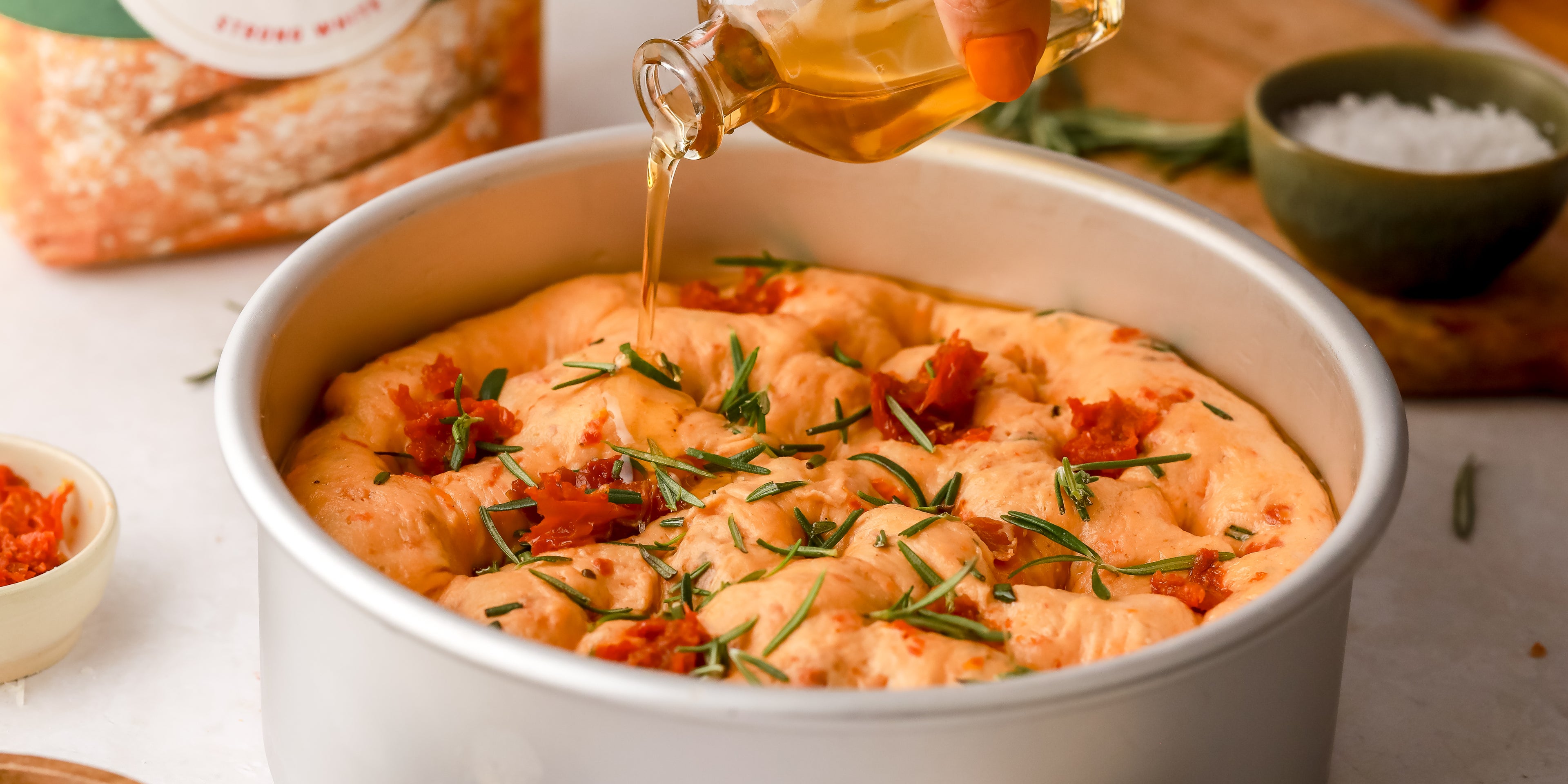 Pouring a small amount of olive oil onto sundried tomato bread