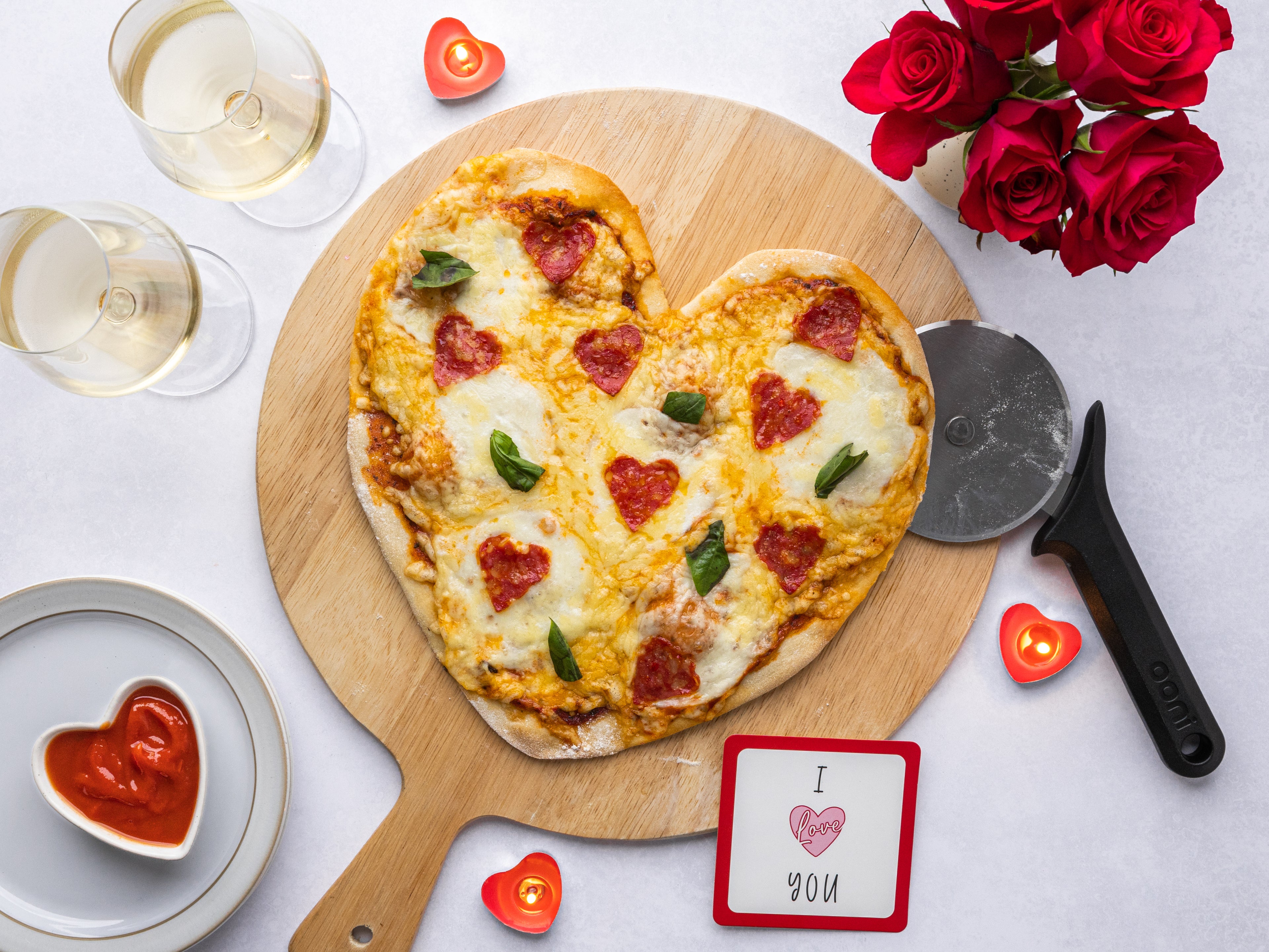 Heart shaped pizza on wooden board with glass of wine and roses