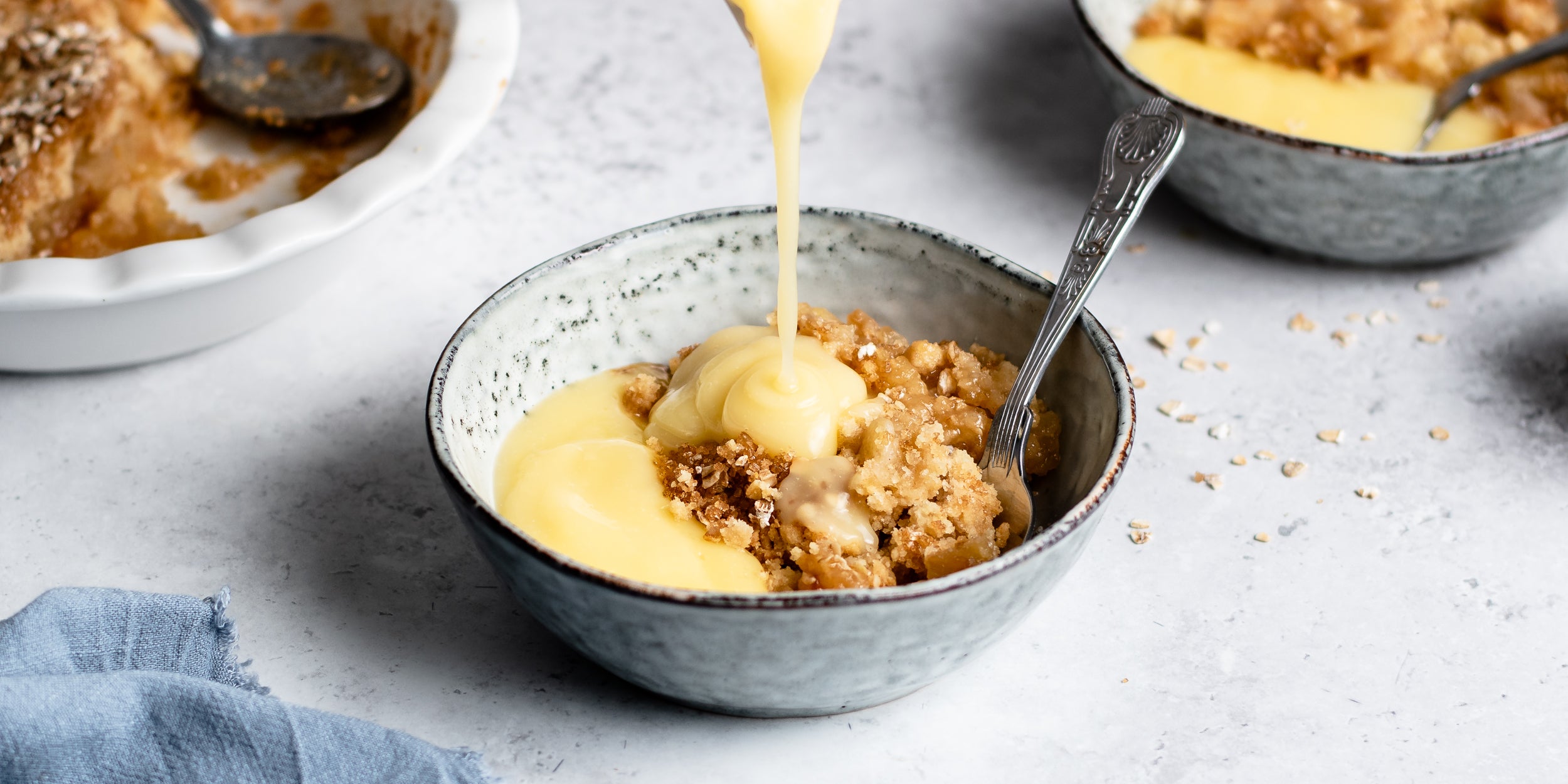 Close up of Ultimate Apple Crumble being drizzled with a generous serving of custard