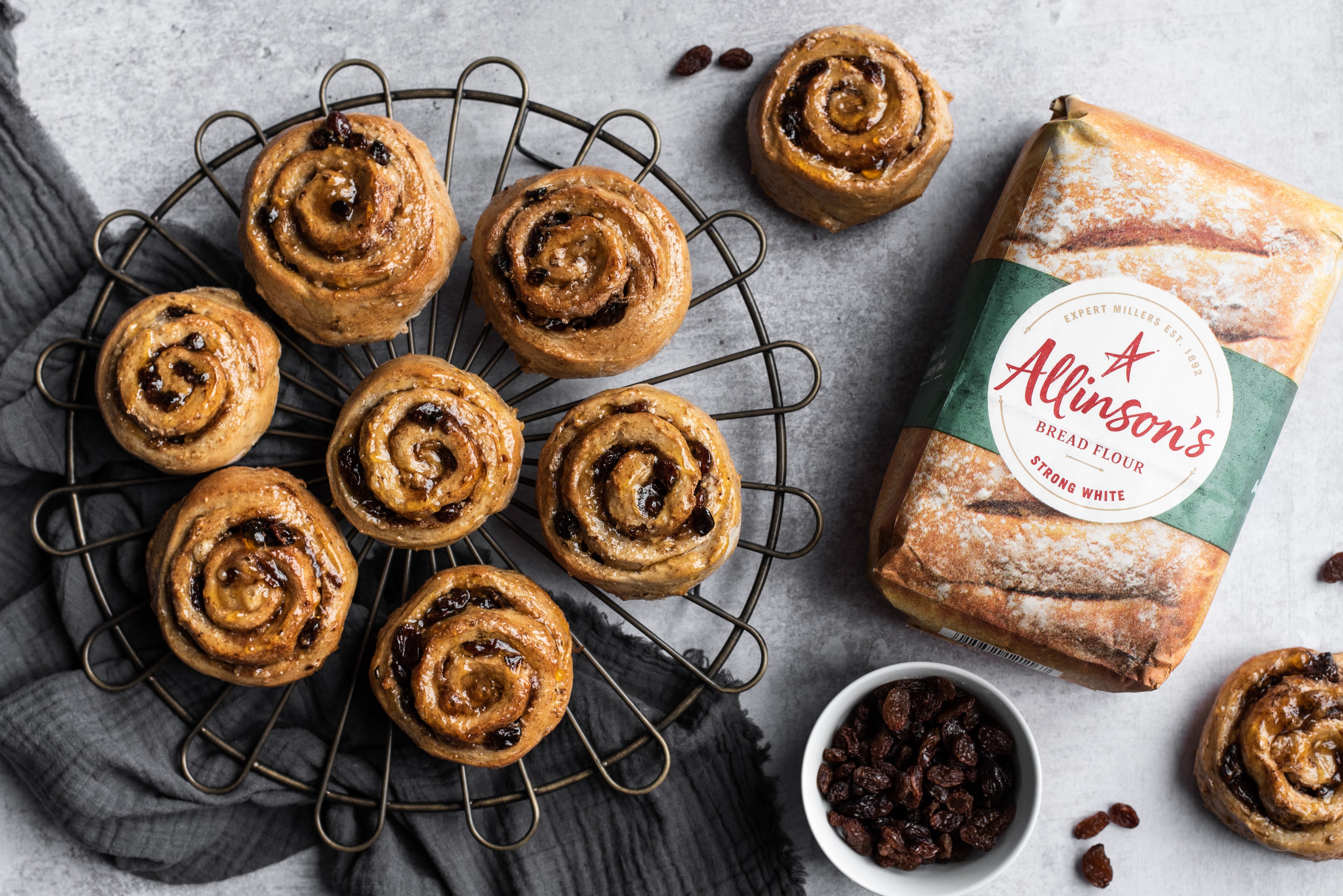 Birds-eye view of Cinnamon Sultana Pinwheels on a cooling rack with two on counter top