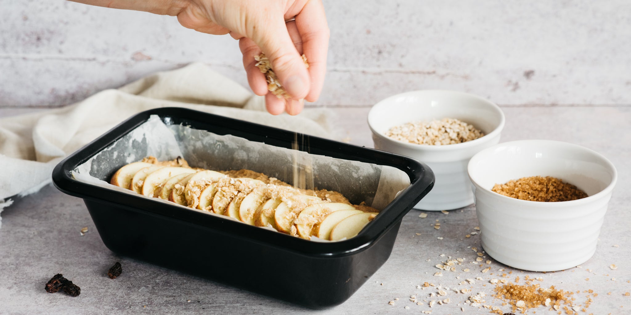 Hand sprinkling sugar on top of cake mixture in tin