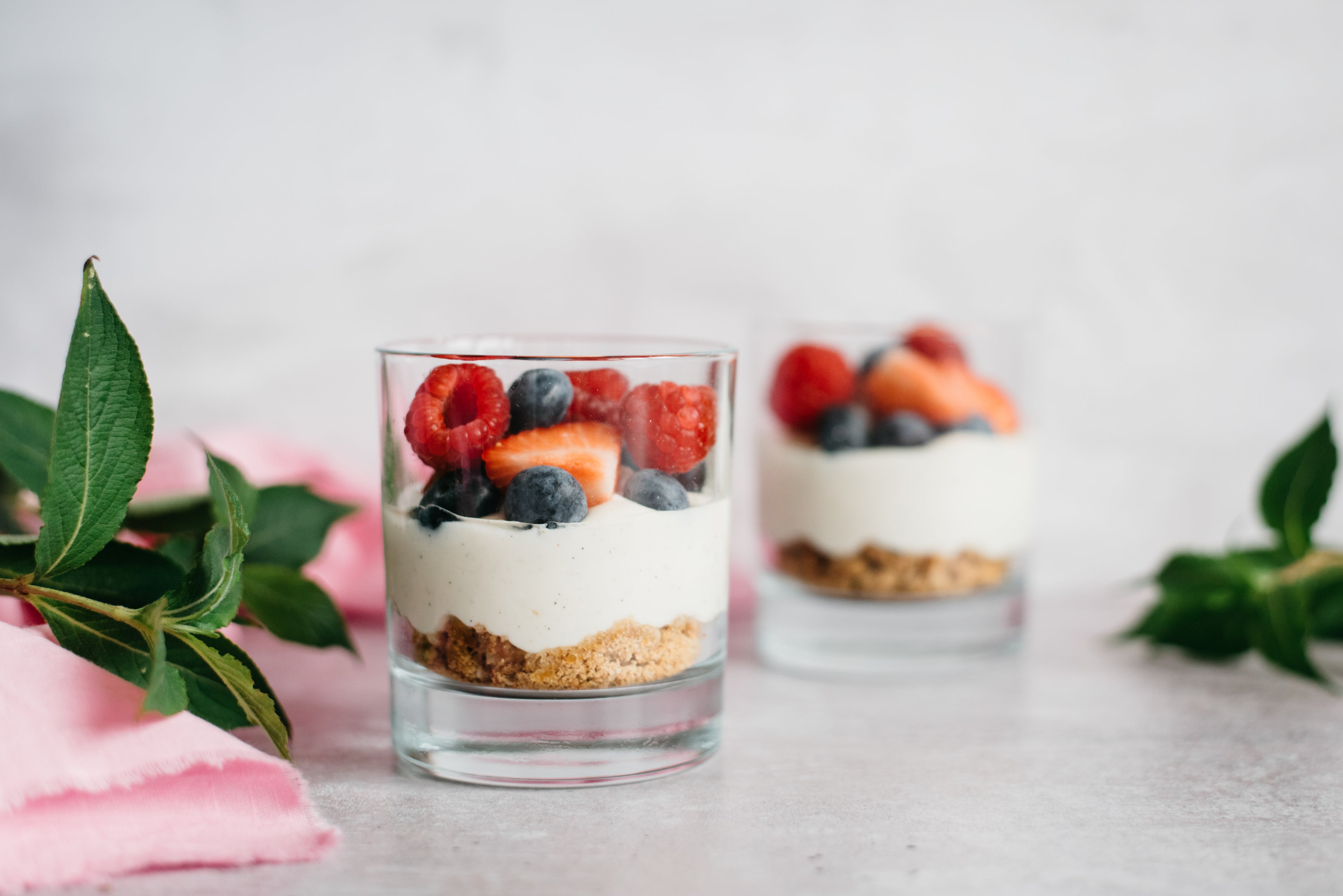 Two honey and berry no bake cheesecakes topped with strawberries and blueberries