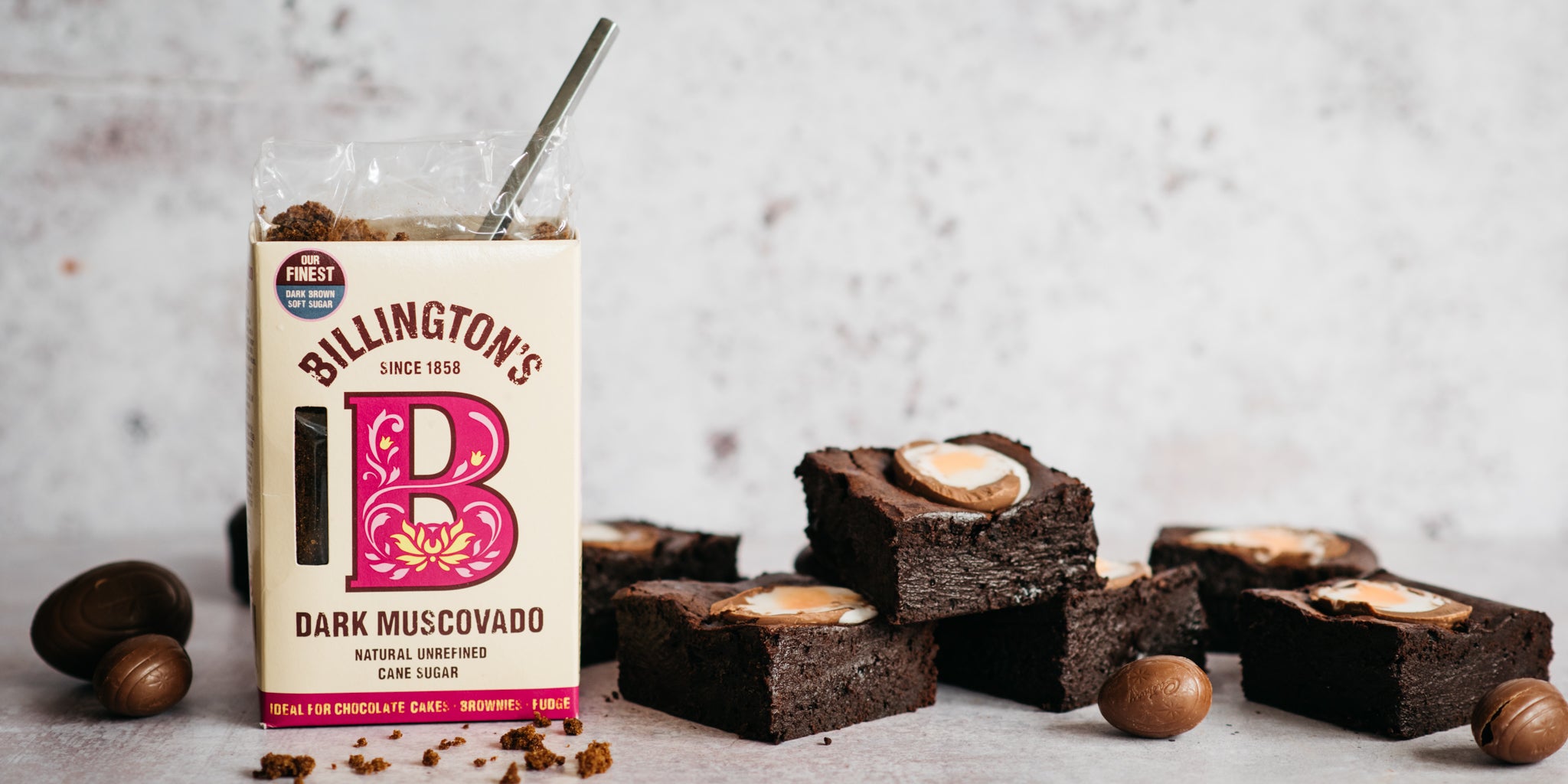 Stacked brownies beside an open pack of Billington's sugar