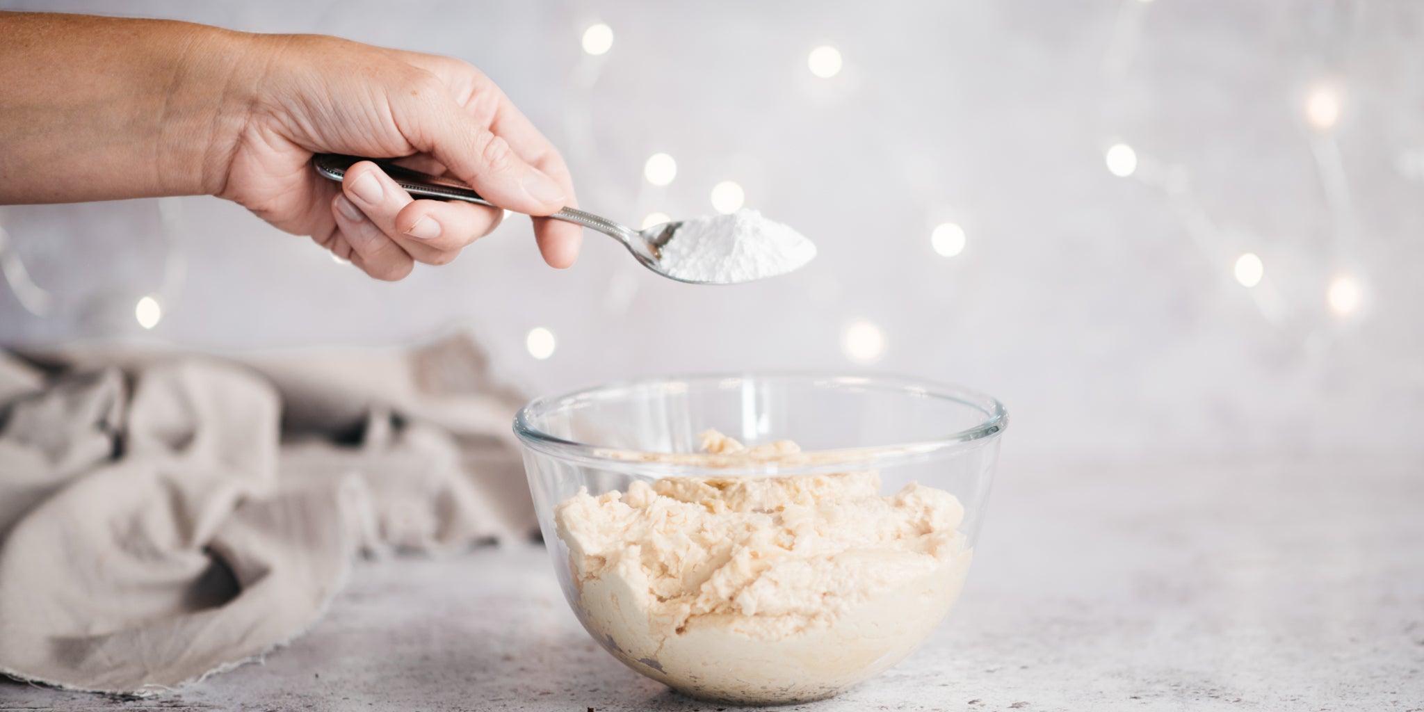 Icing sugar being sprinkled into bowl of butter cream icing