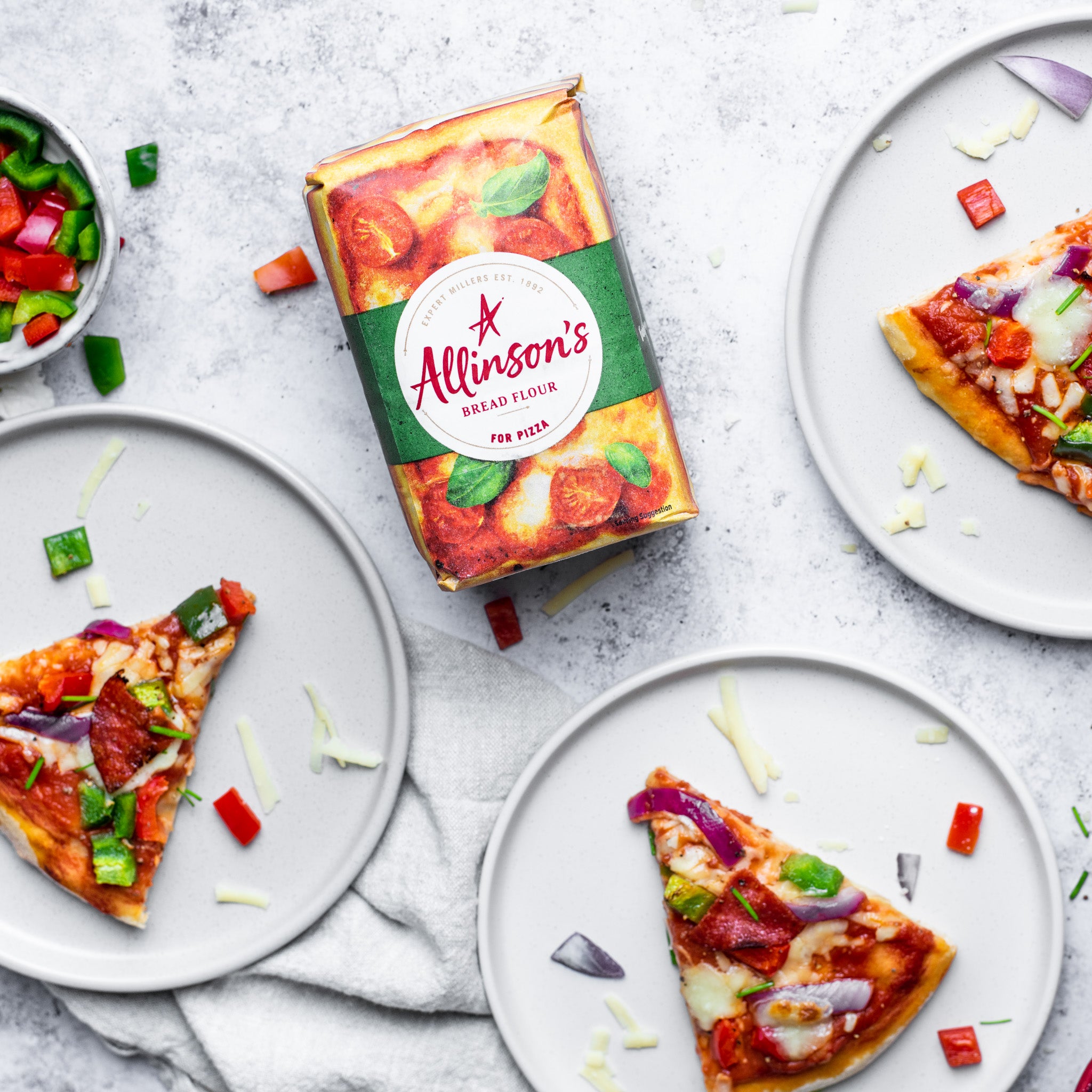 A top down view single pizza slices on plates next to a pack of allinson's bread flour for pizza dough