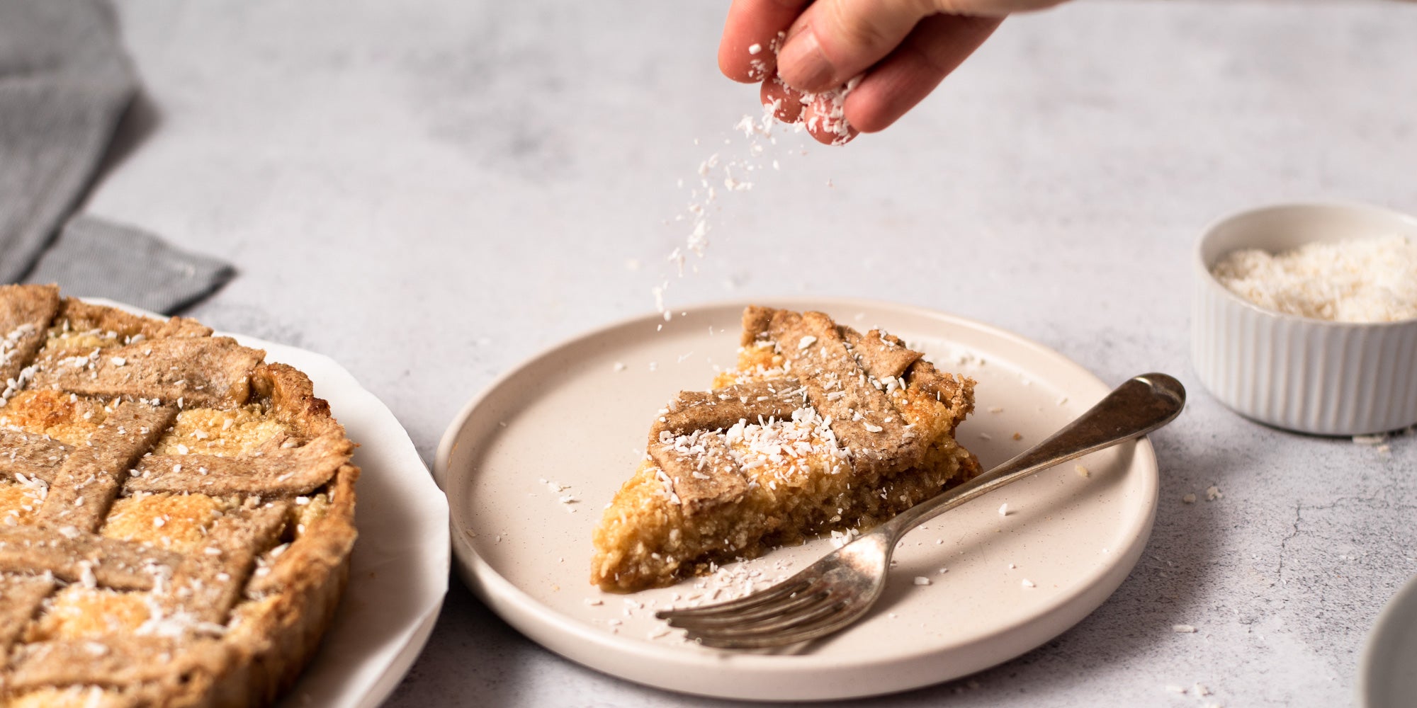 coconut being sprinkled over coconut tart