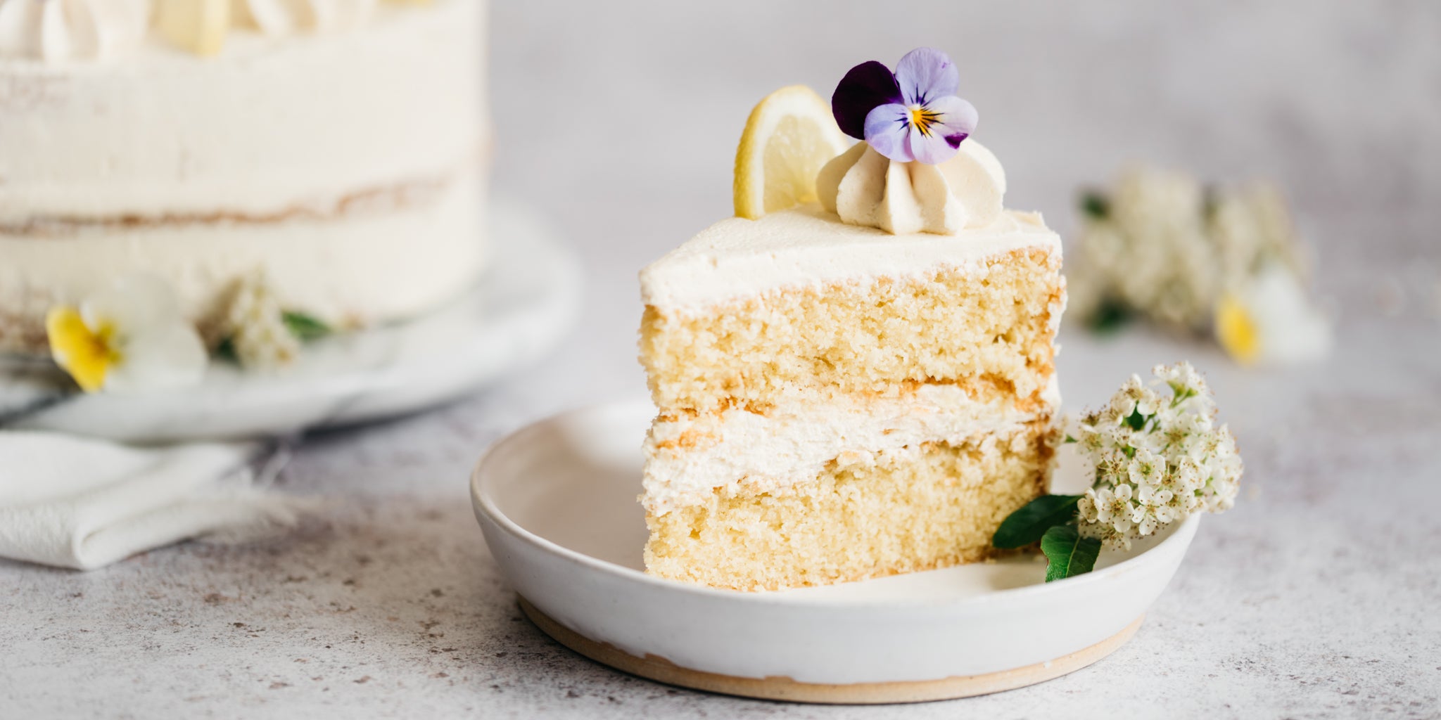 Close up of slice of cake topped with flowers in a white bowl