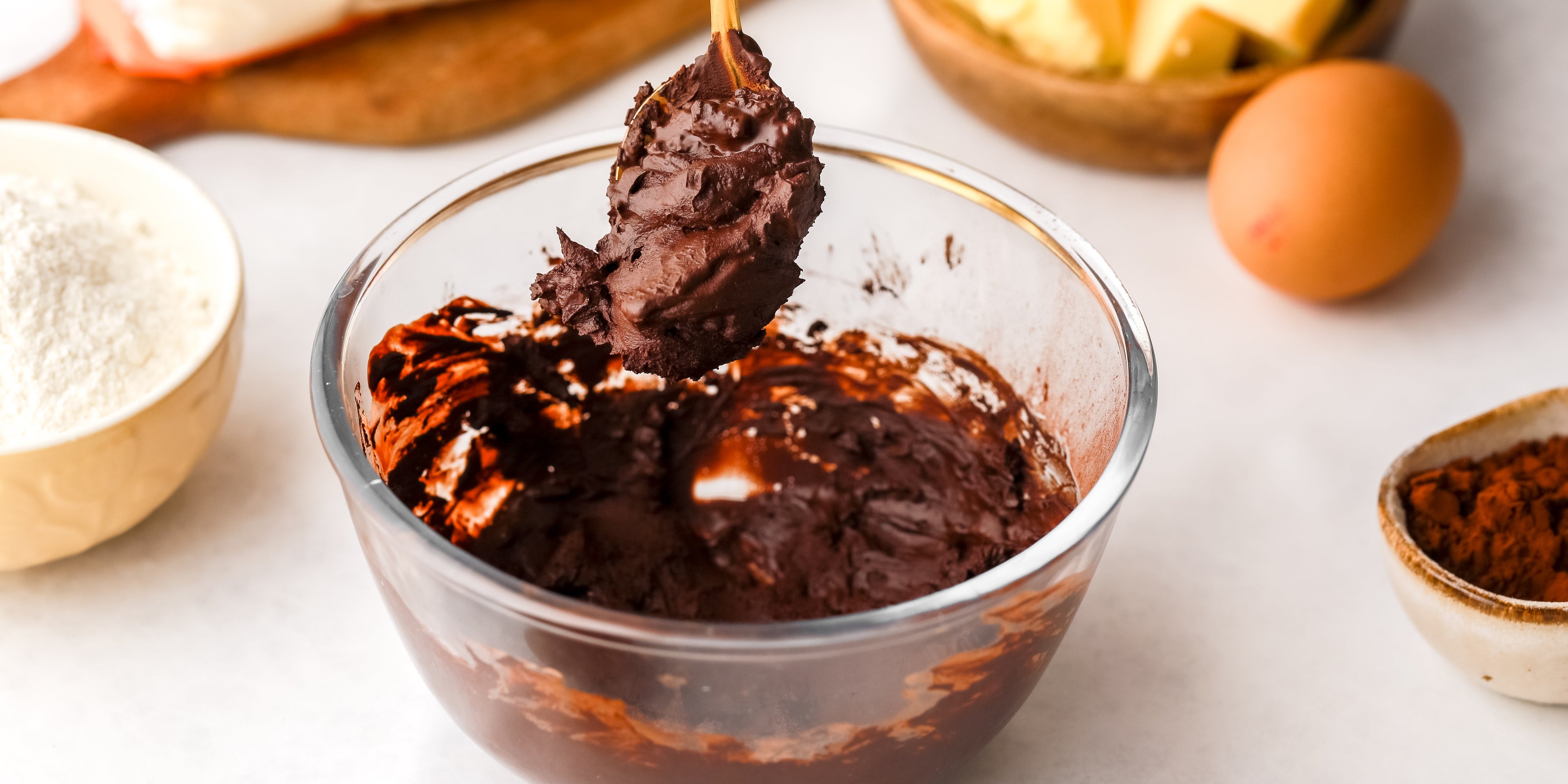 Chocolate buttercream being mixed in a glass bowl