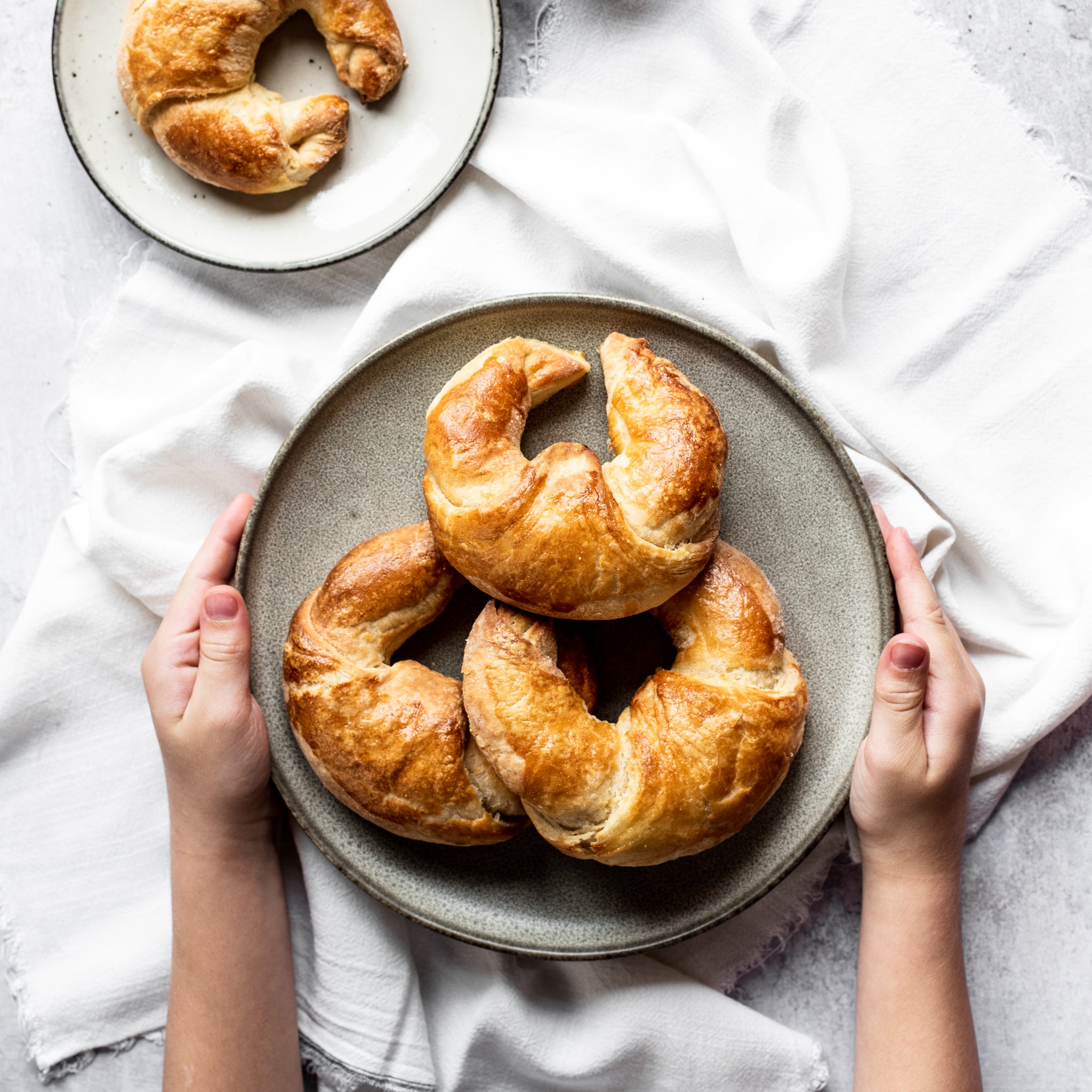 Plate of 3 croissants with two hands holding each side