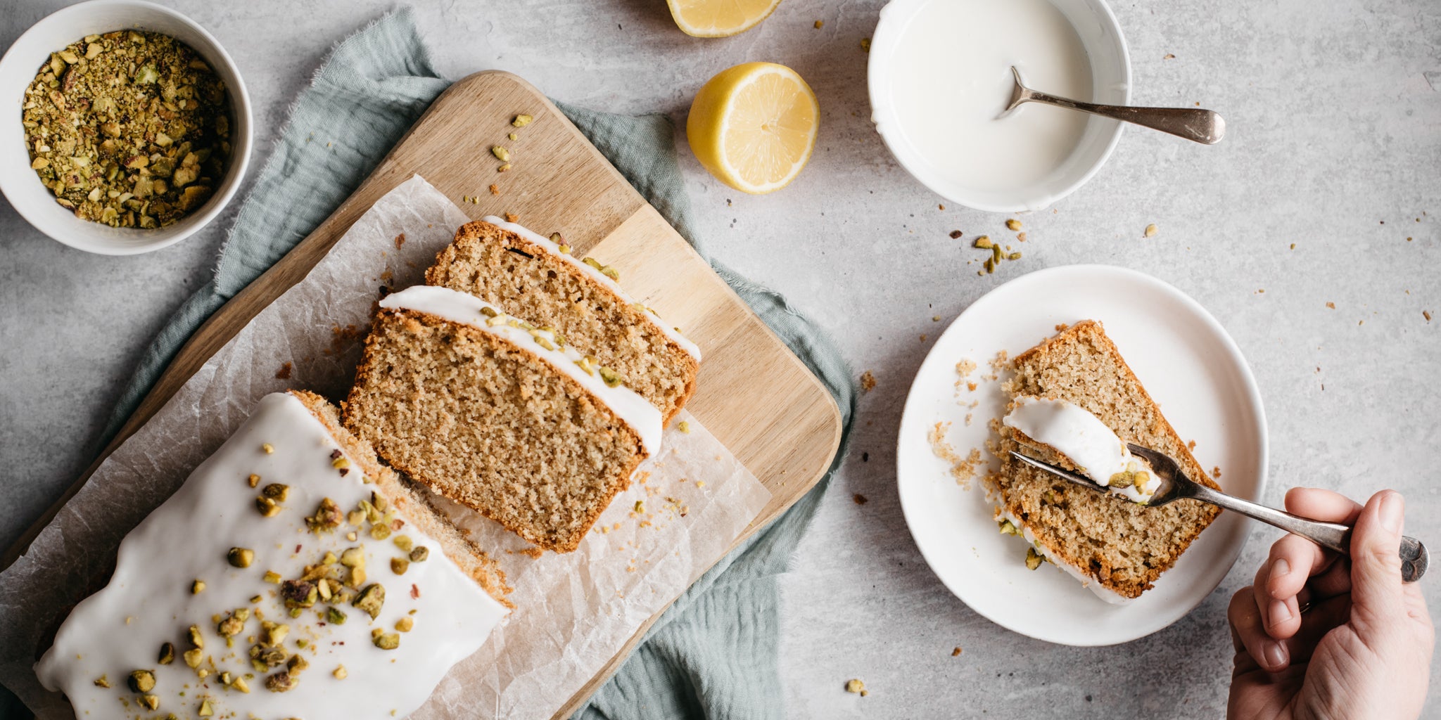 Gluten Free Vegan Lemon Drizzle Cake sliced into servings with someone enjoying a piece with a fork