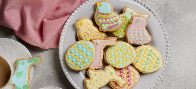 Mix of pastel coloured easter biscuits on a white plate
