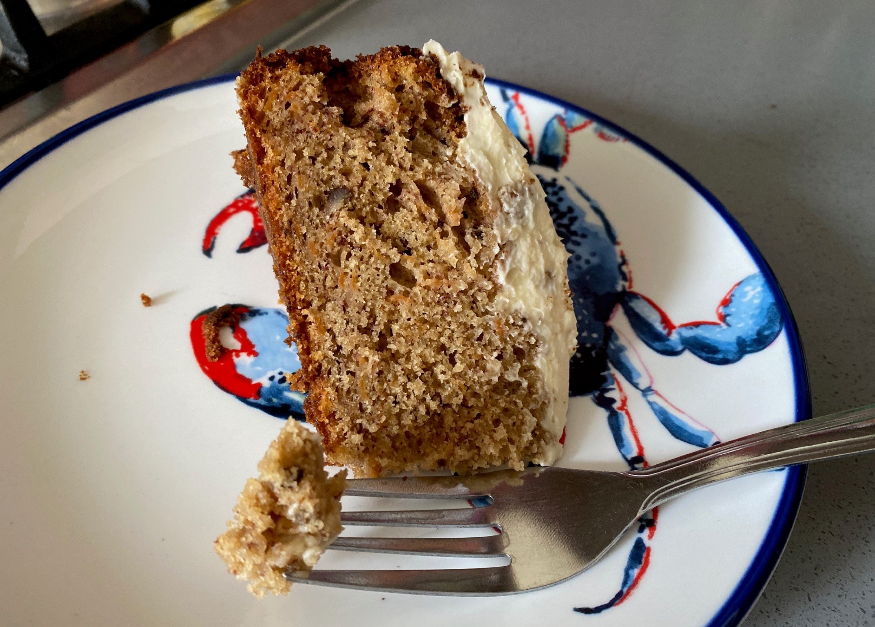 Slice of Mary Berry's carrot cake on a plate with a forkful of cake resting nearby