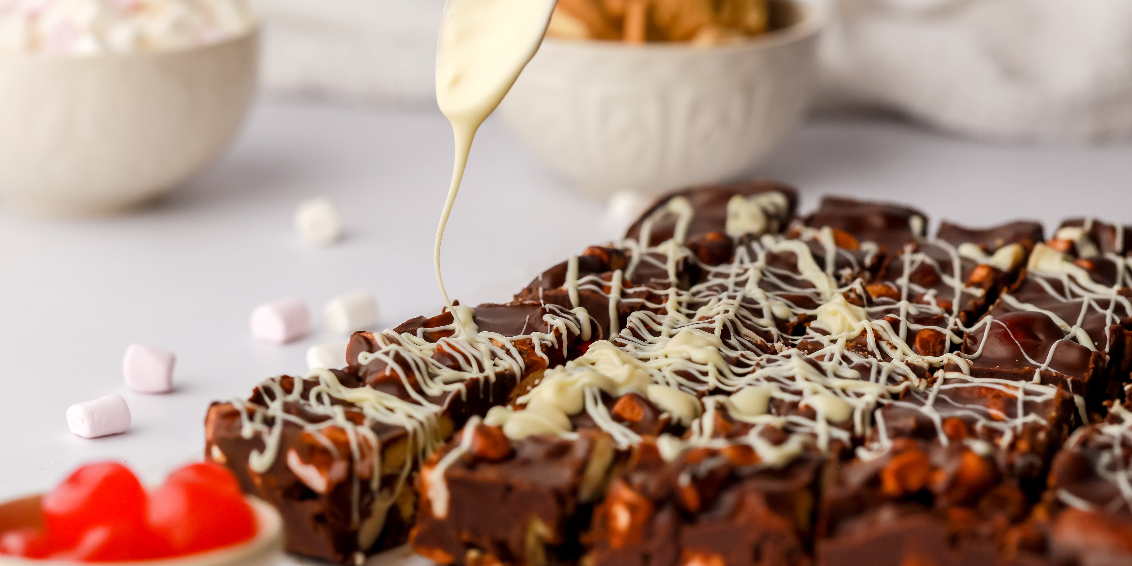 White chocolate being drizzled on top of rocky road