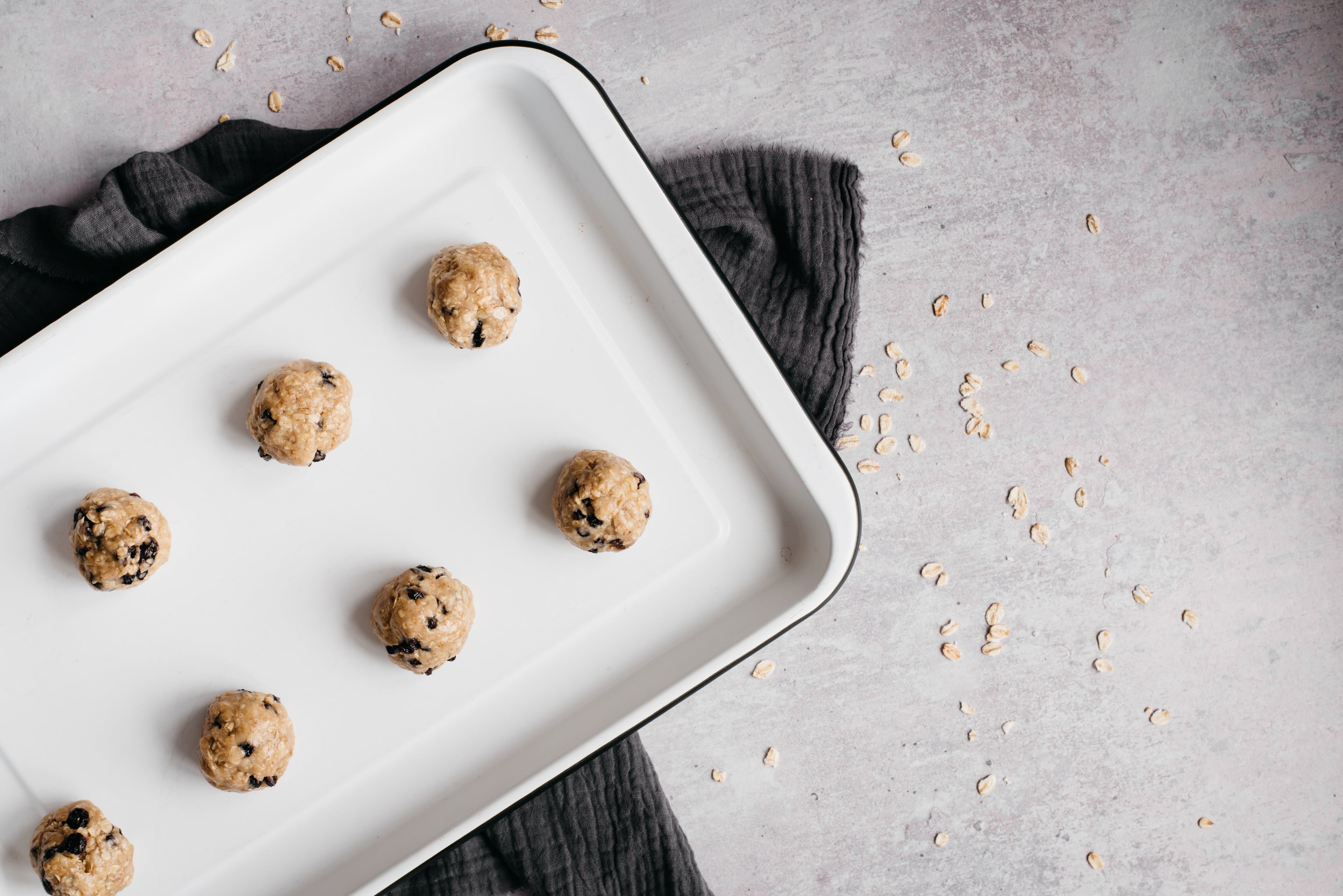 Oat & Raisin Cookies being portioned into balls in a baking tray ready to bake in the oven