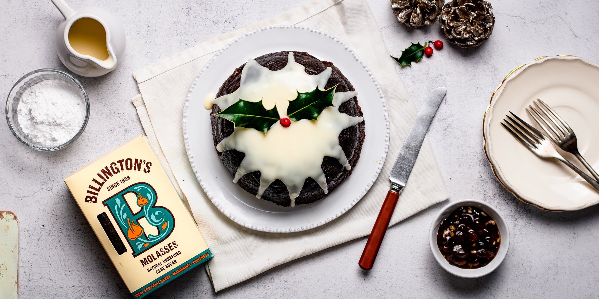 Top view of Last Minute Christmas Pudding next to a box of Billington's Molasses and a jug of brandy butter