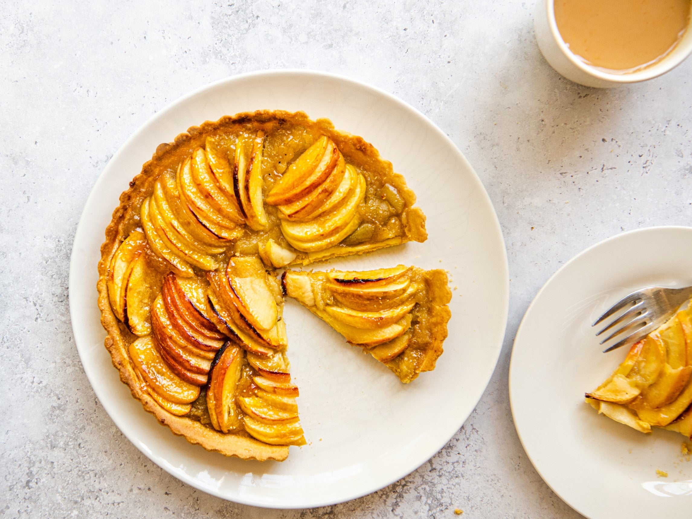 Apple tart on a white plate with a slice cut out