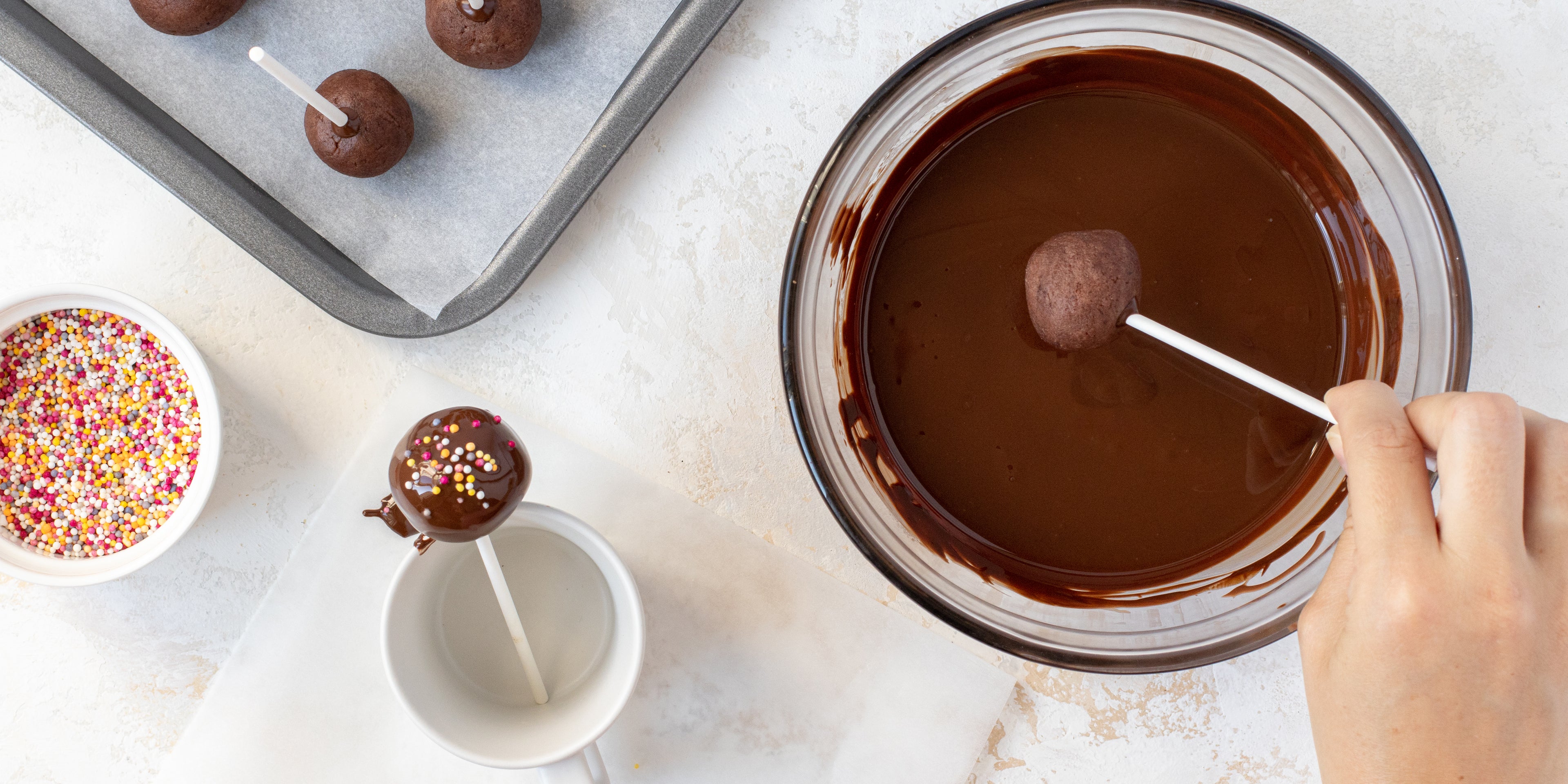 Chocolate Cake Pop on a stick being dipped into chocolate icing and sprinkles and left to set 