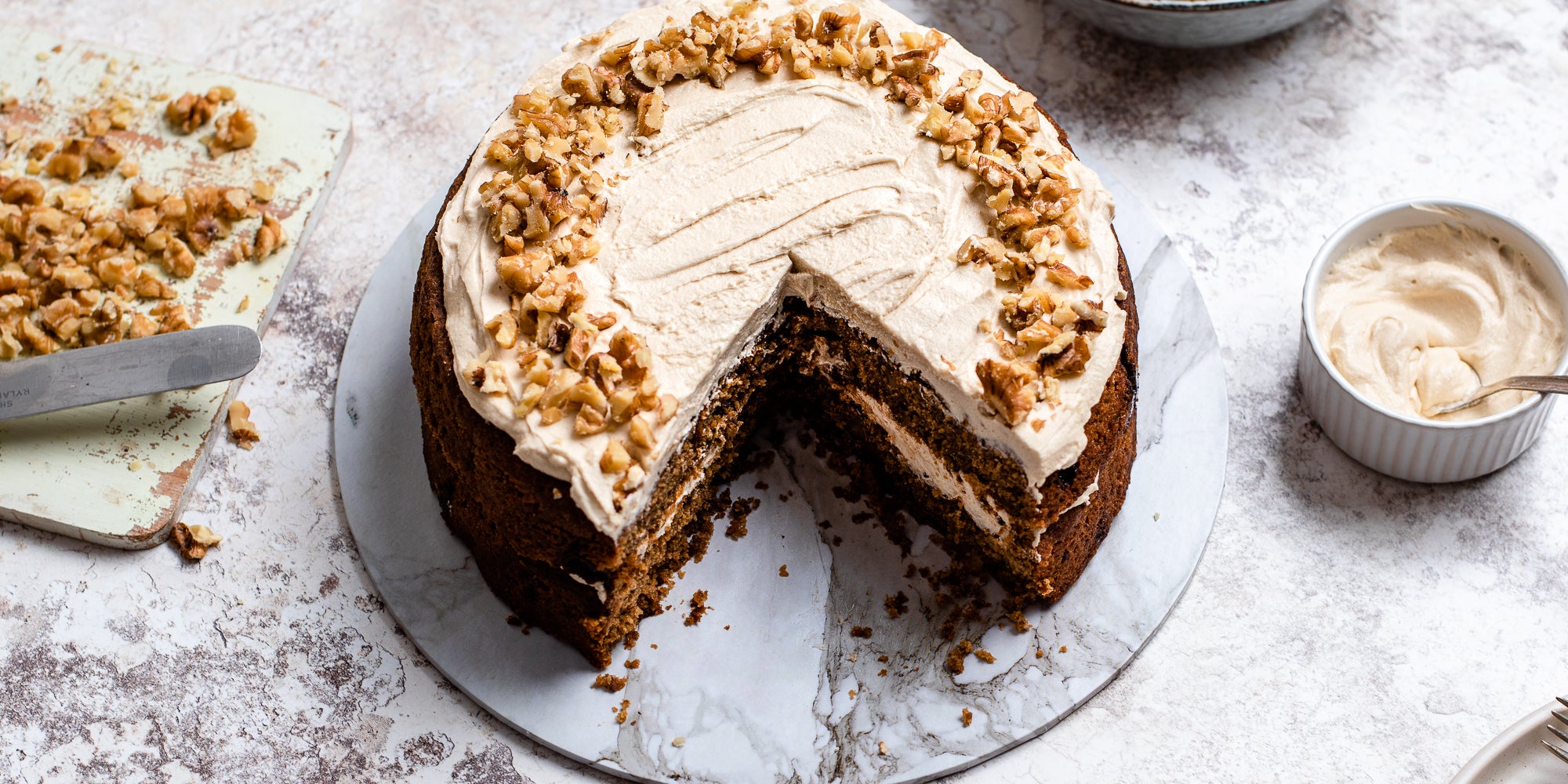 Gluten Free Vegan Coffee Cake close up, with a slice cut out of it, next to a ramekin of buttercream
