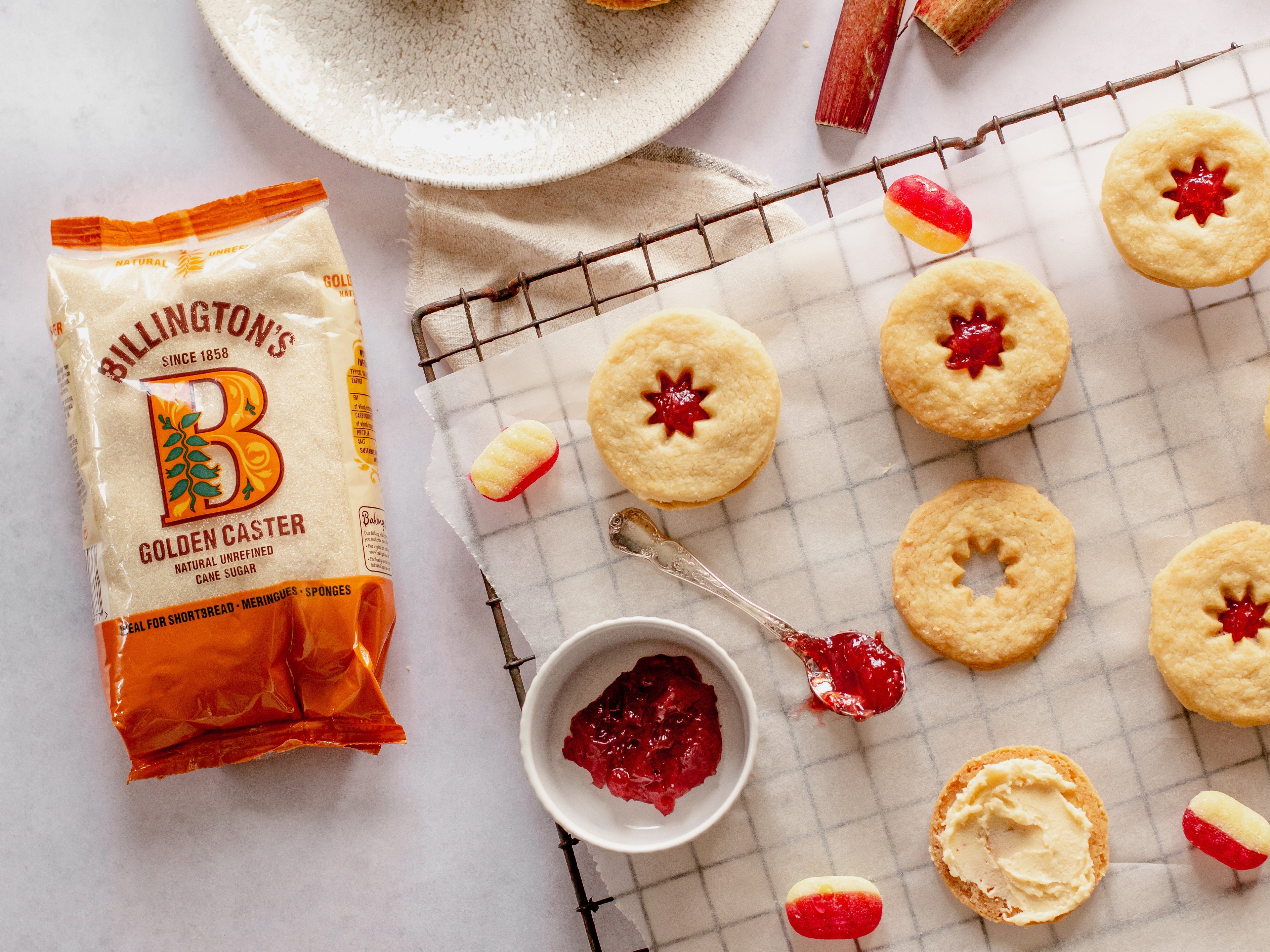 Overhead shot of jammy dodger biscuits being assembled. Sweets, jam in bowl and jammy spoon. Sugar pack in shot