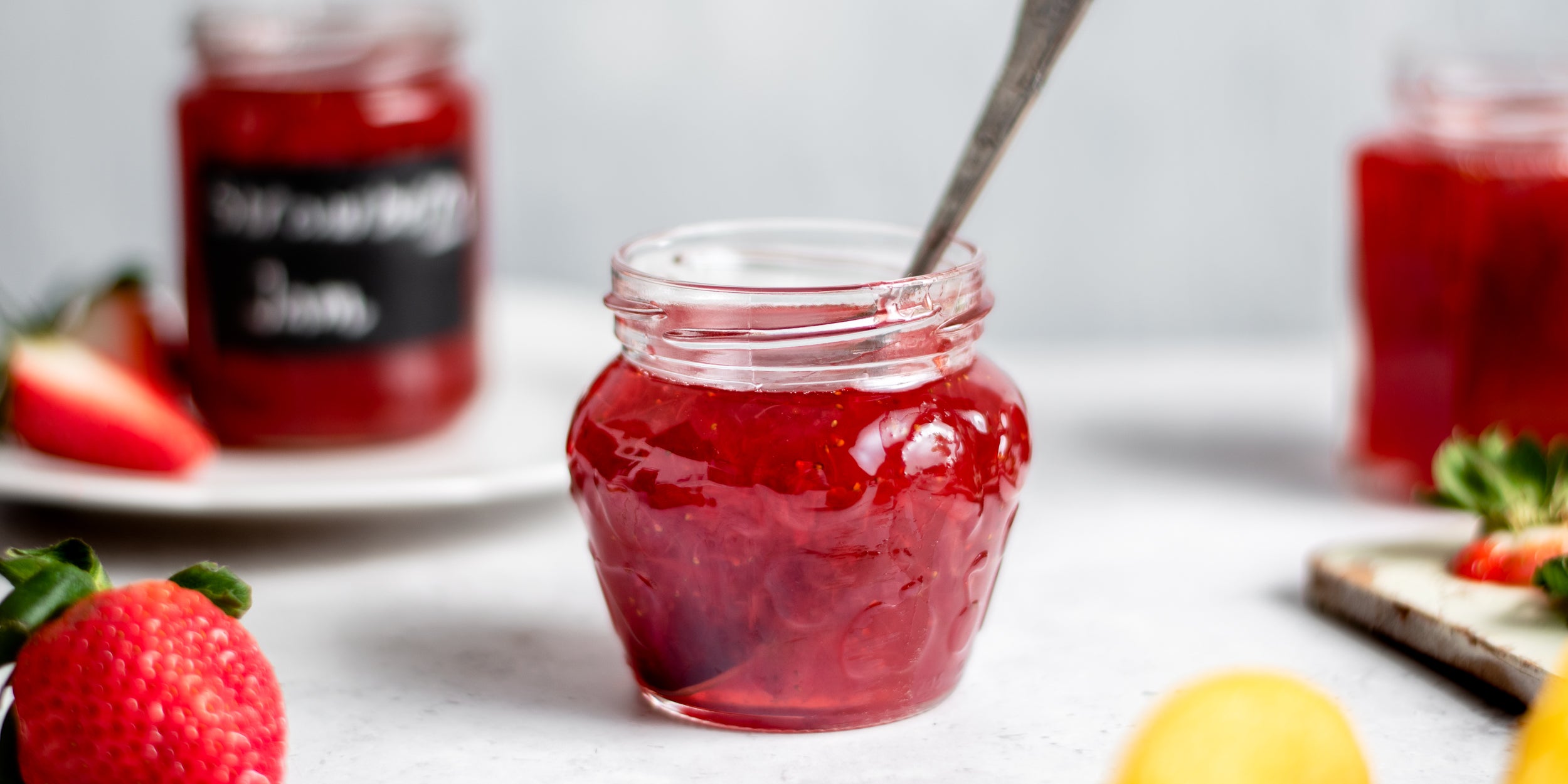 Close up of Strawberry Jam in a jam jar, with a spoon in it ready to serve