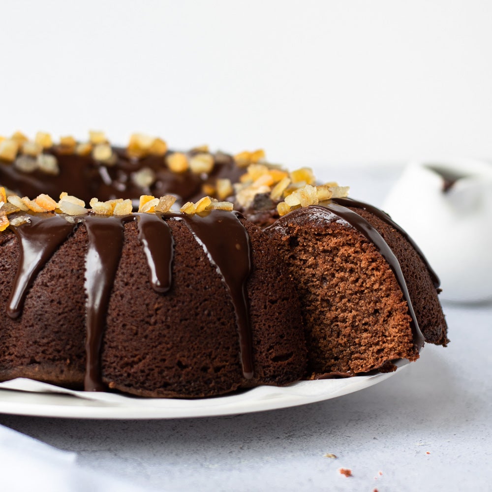 chocolate orange bundt cake on plate with chocolate drizzle on top with candid orange peel