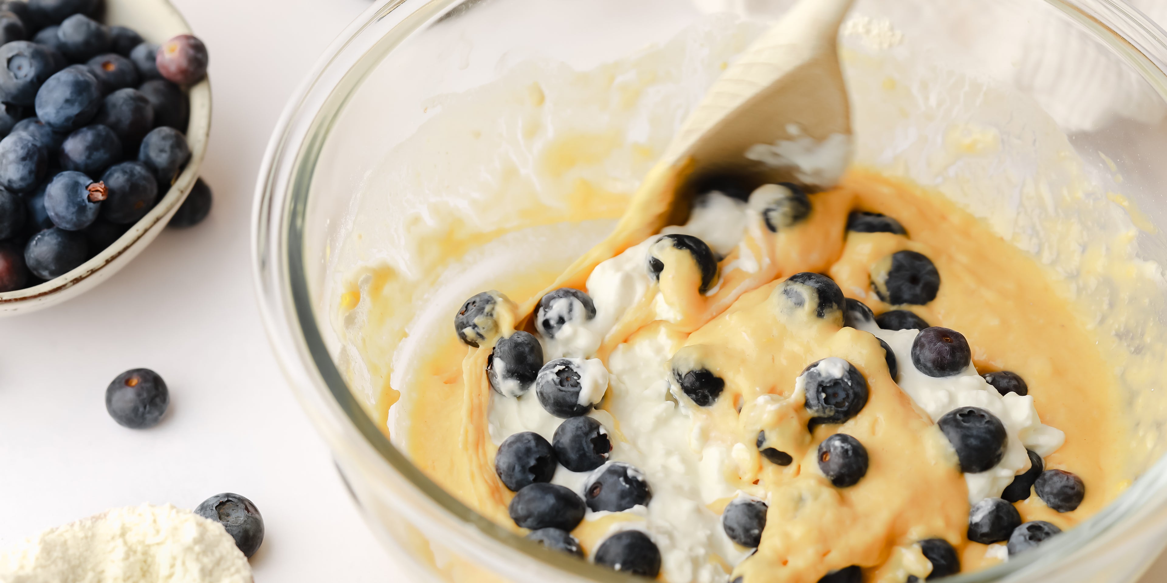 Pancake batter in a mixing bowl with a spoon and blueberries